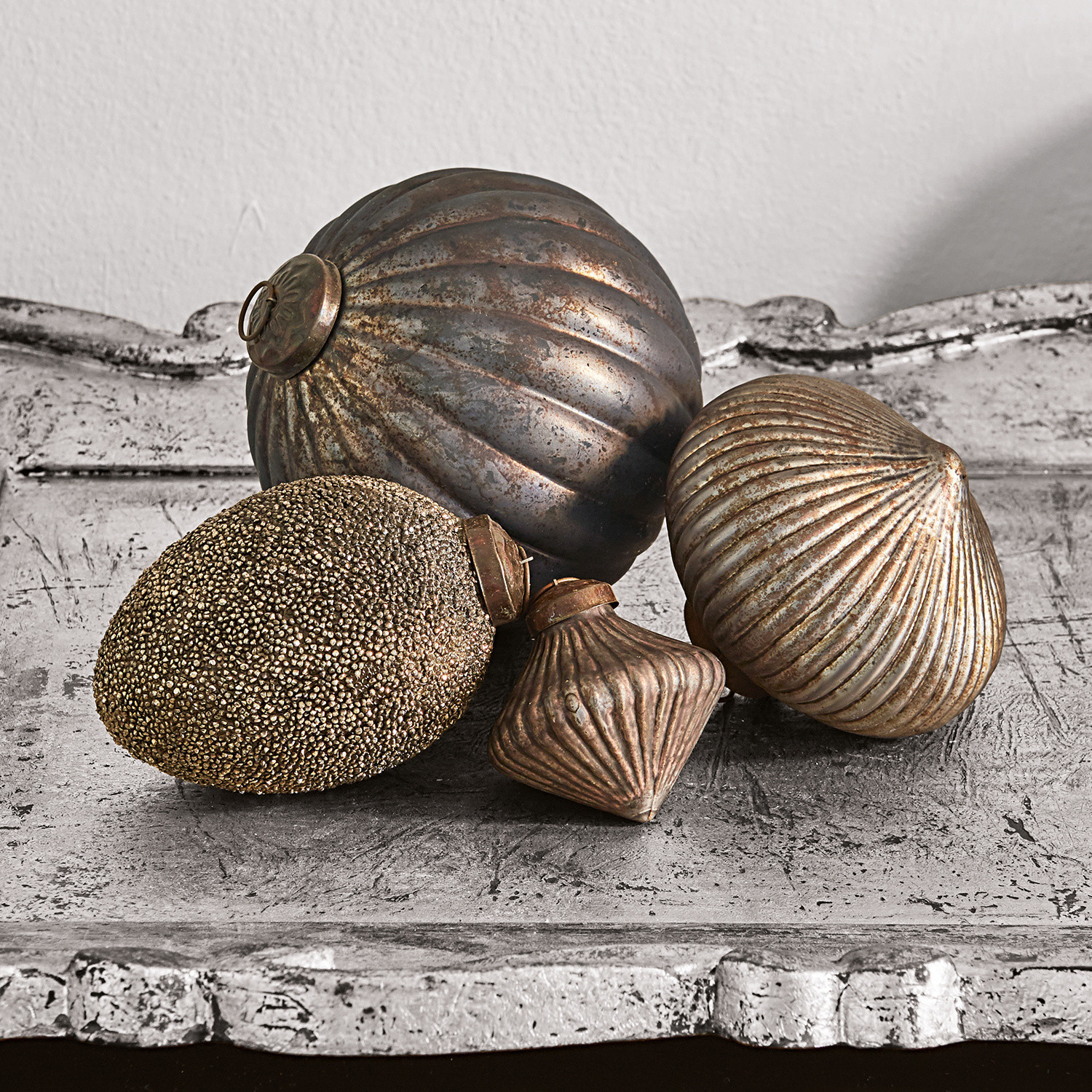 Lot de 4 décorations de Noël Janine Ensemble de quatre décorations métalliques dorées vieilles posées sur une surface patinée