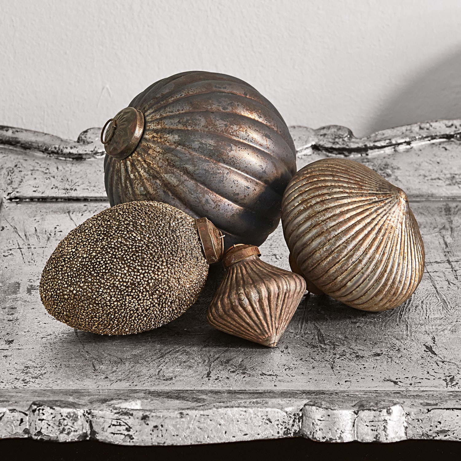 Lot de 4 décorations de Noël Janine Ensemble de quatre décorations métalliques dorées vieilles posées sur une surface patinée