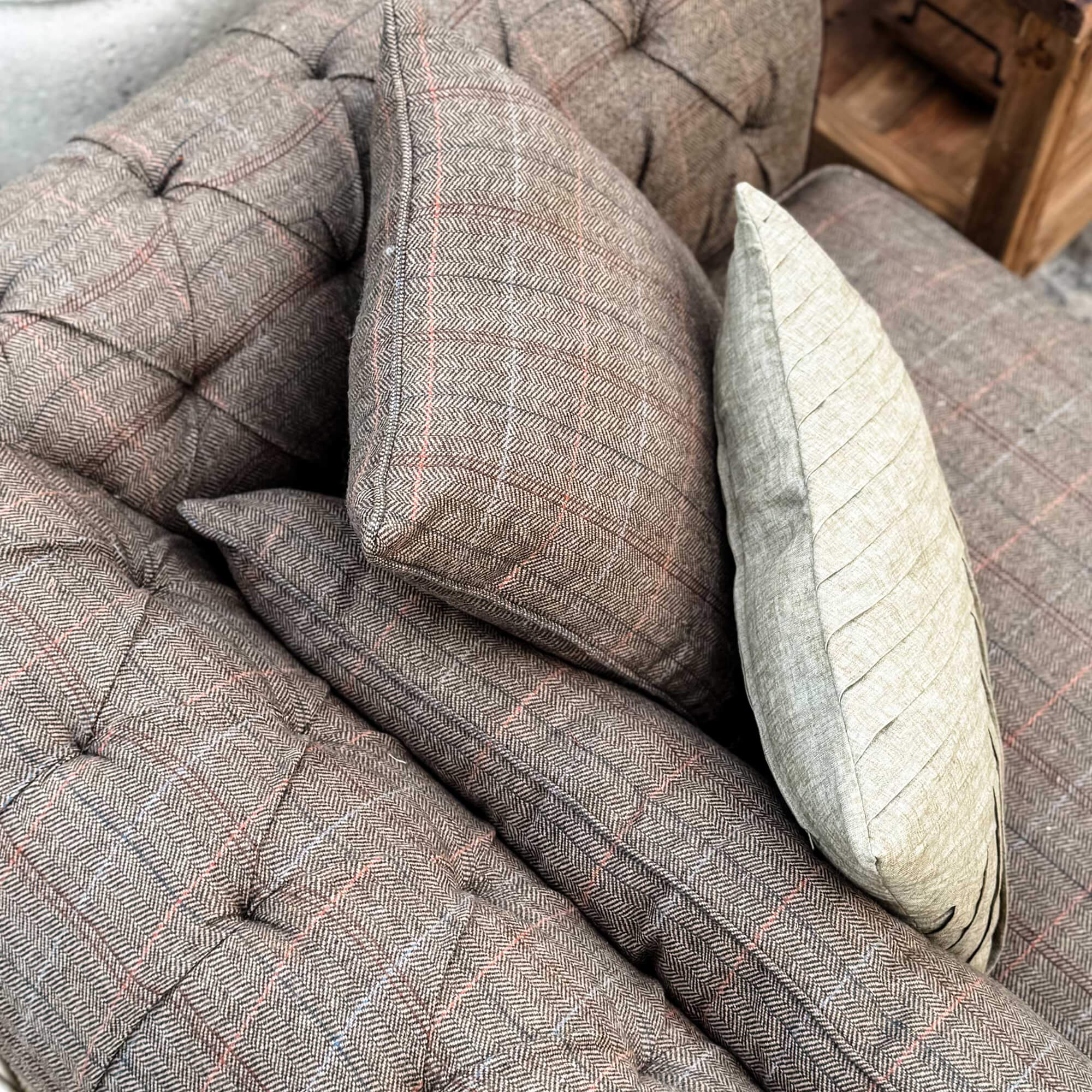 Canapé rembourré marron avec coussins à motif chevrons et coussin décoratif clair en tissu