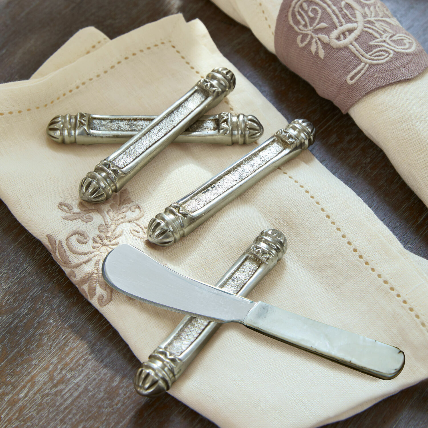 Lot de 4 porte-couteaux Lafox Sous-couteaux en métal argenté sur une serviette crème brodée, ensemble de table élégant