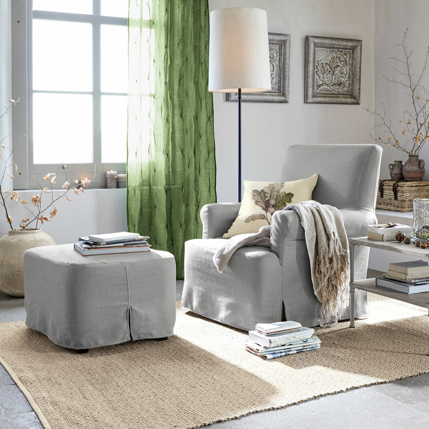 Fauteuil avec pouf Nasour Fauteuil gris avec repose-pieds assorti et rideaux verts dans un salon lumineux avec tapis en jute