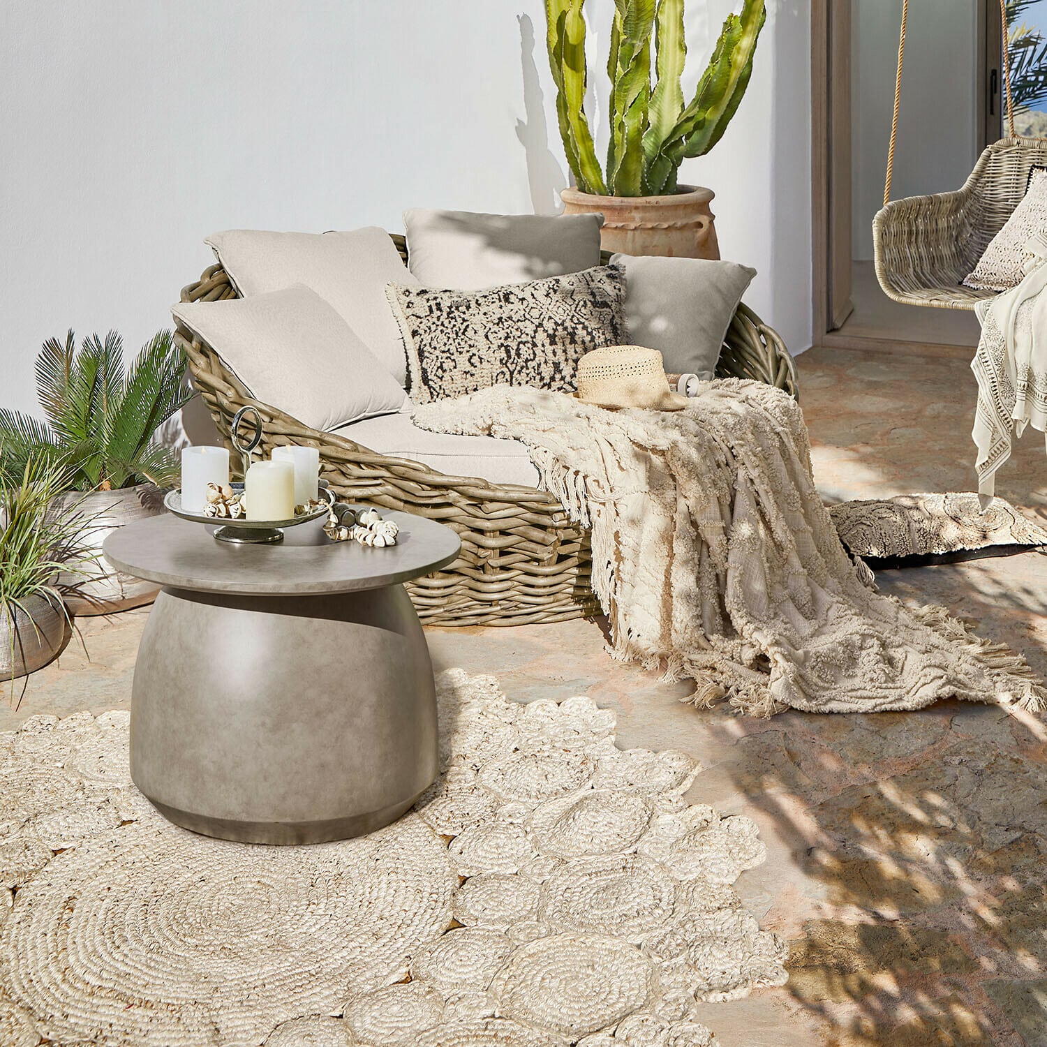 Tapis d’intérieur et d’extérieur Norlinn Table basse ronde en béton sur terrasse avec canapé en osier et plaid crème décoratif