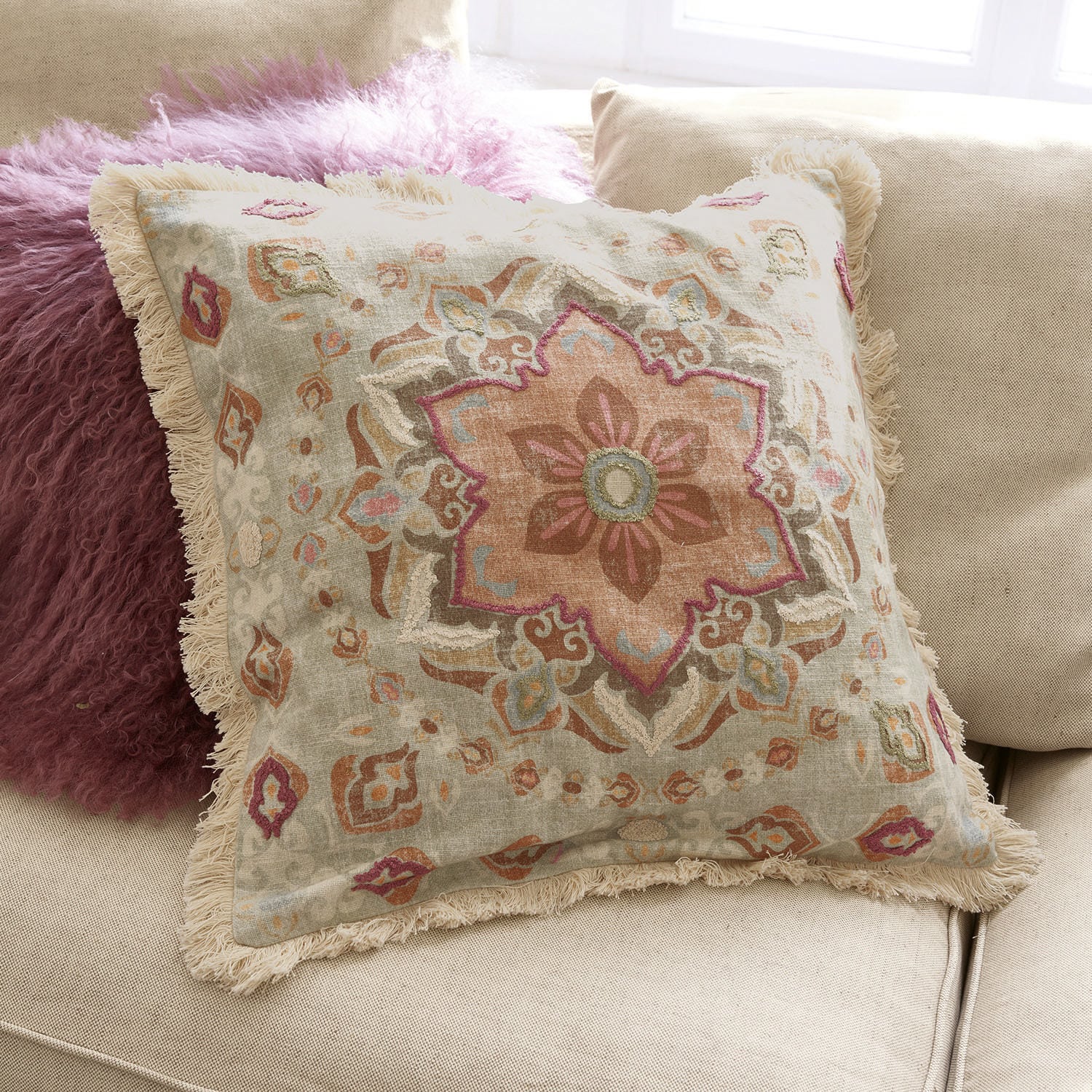 Coussin Garchy Coussin décoratif en coton avec franges et motif pastel sur canapé beige