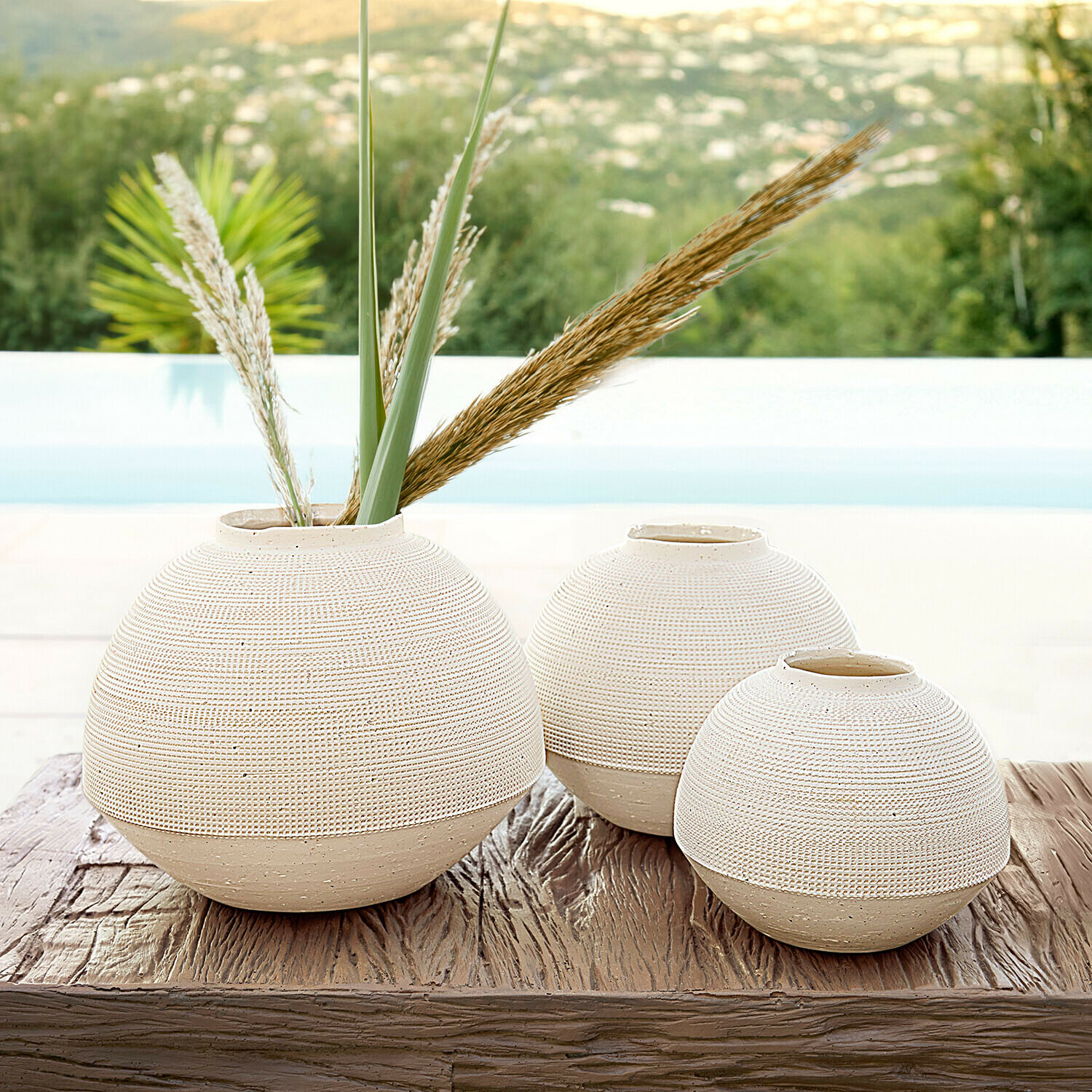 Ensemble de trois vases ronds en céramique beige sur une table en bois, décoration intérieure élégante