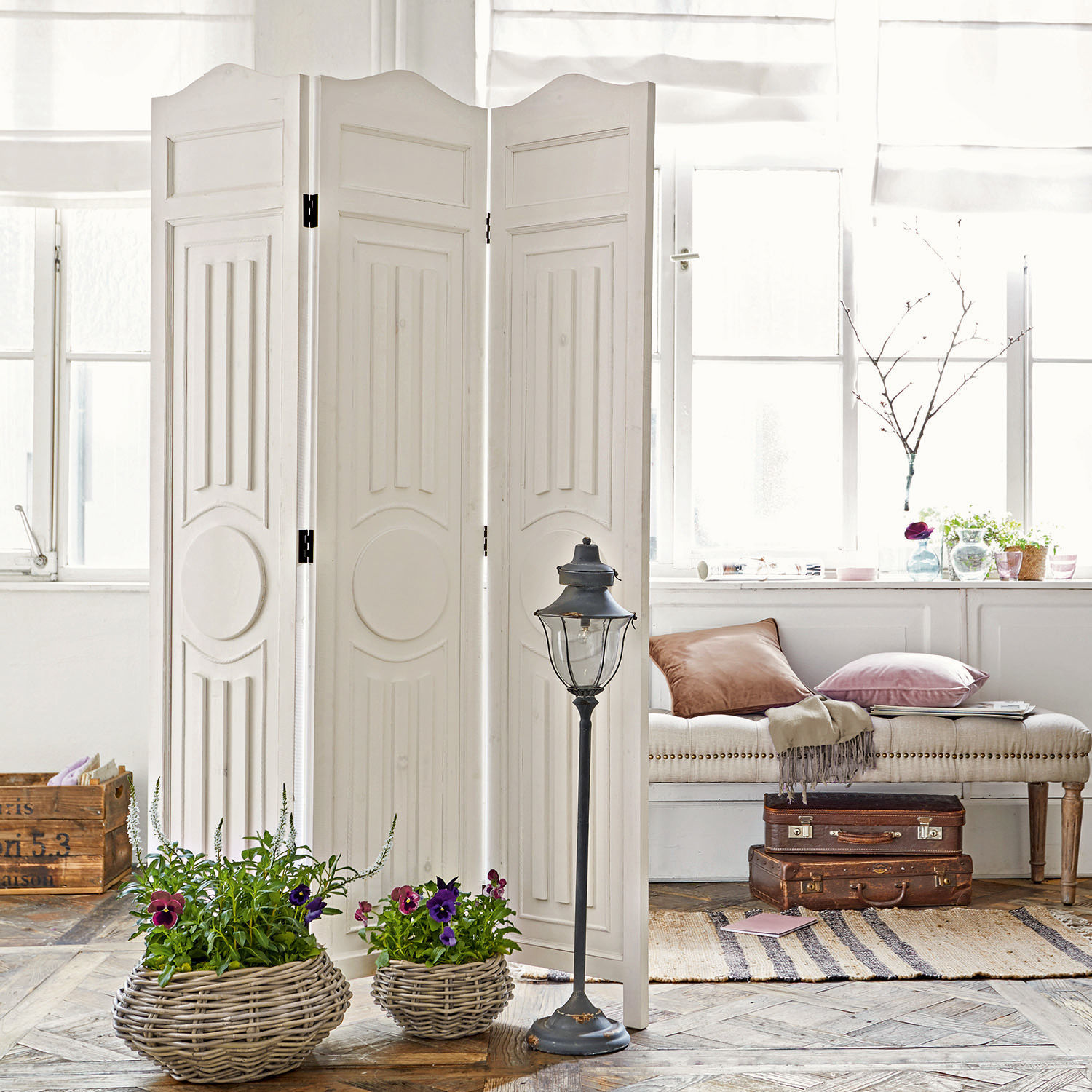 Paravent Perineau Paravent en bois blanc avec panneaux décoratifs dans un intérieur lumineux avec pots en osier et coussins