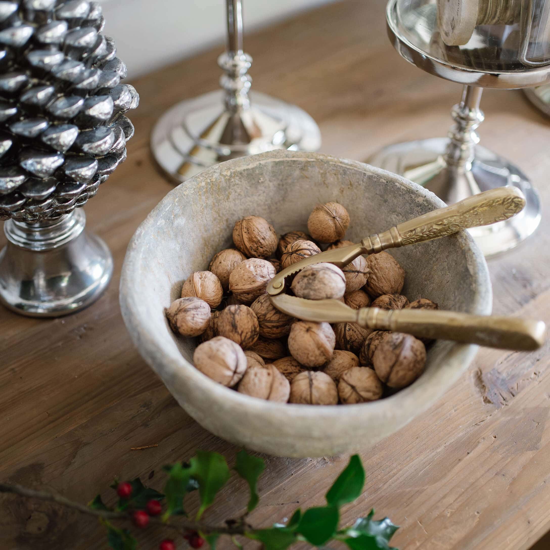 Bol en pierre avec noix et casse-noix doré sur une table en bois rustique