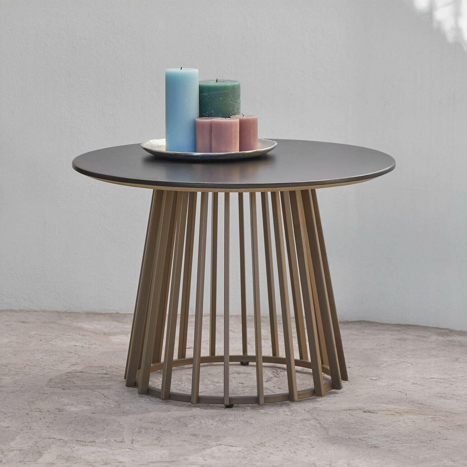Table d"appoint Olianne Table basse ronde avec plateau noir en métal et base en barres brunes, décorée de bougies colorées
