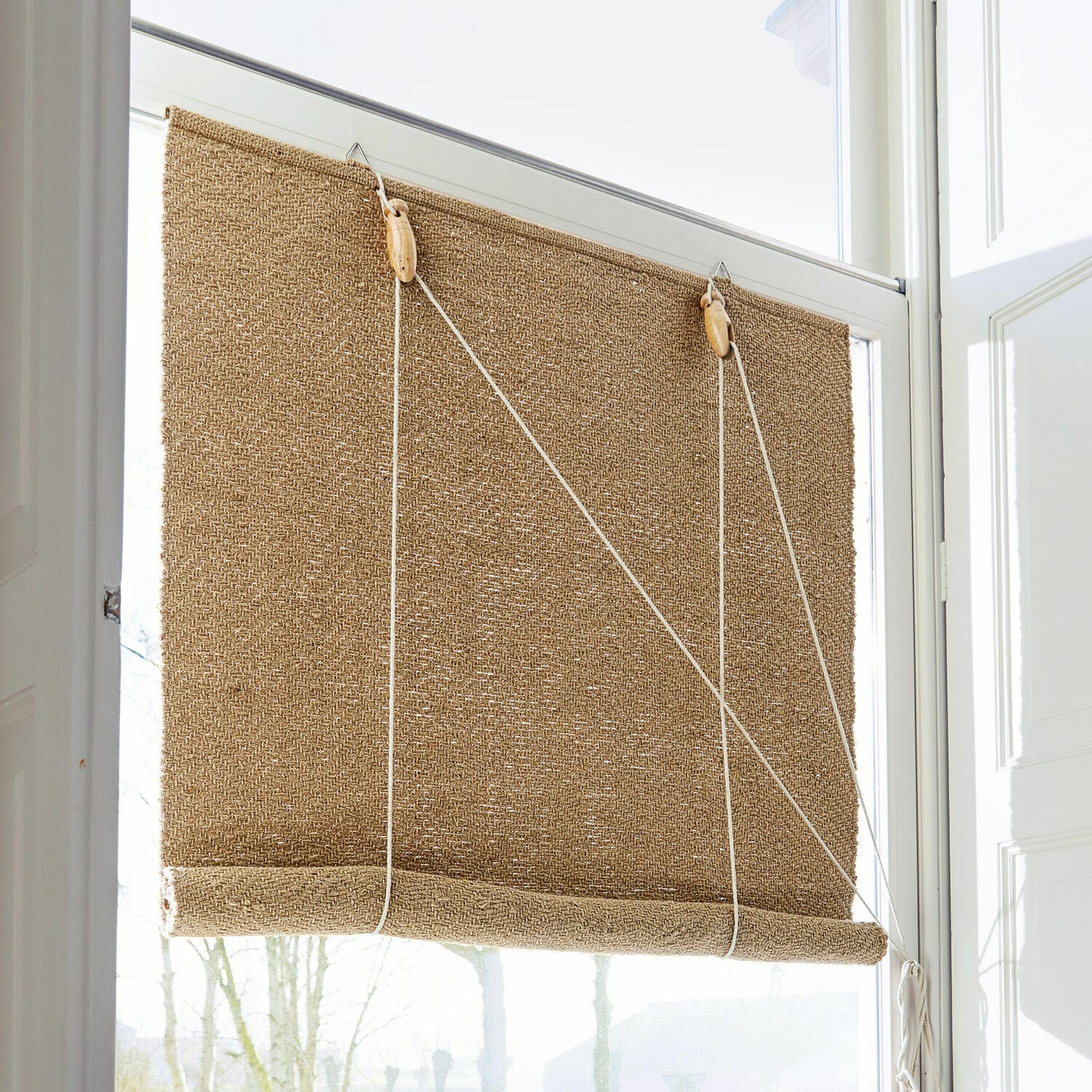 Store enrouleur Paine Store en toile de jute beige naturel avec cordon et éléments en bois pour réguler la lumière