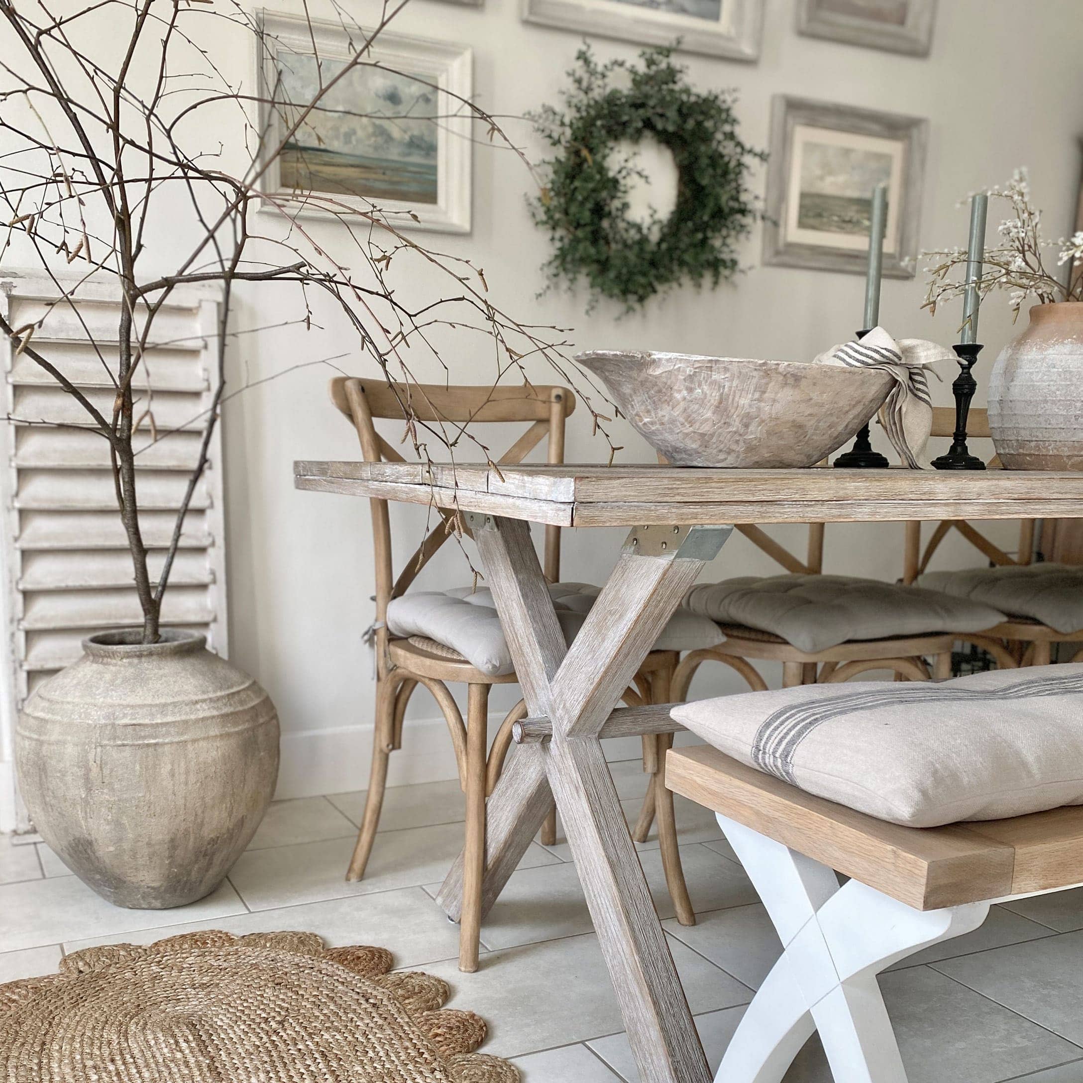 Salle à manger avec table en bois clair, chaises assorties, décorations naturelles et coussins