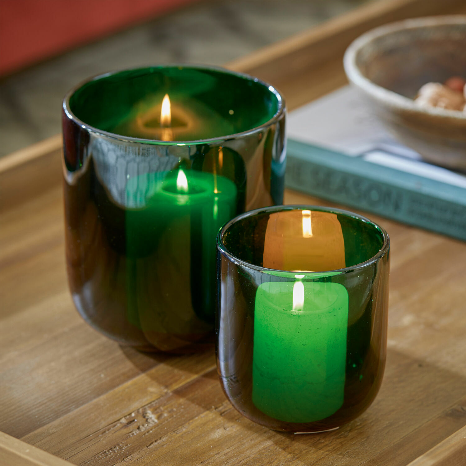 Lot de 2 photophores Theodor Deux photophores en verre vert avec bougies allumées sur une table en bois, décoration intérieure