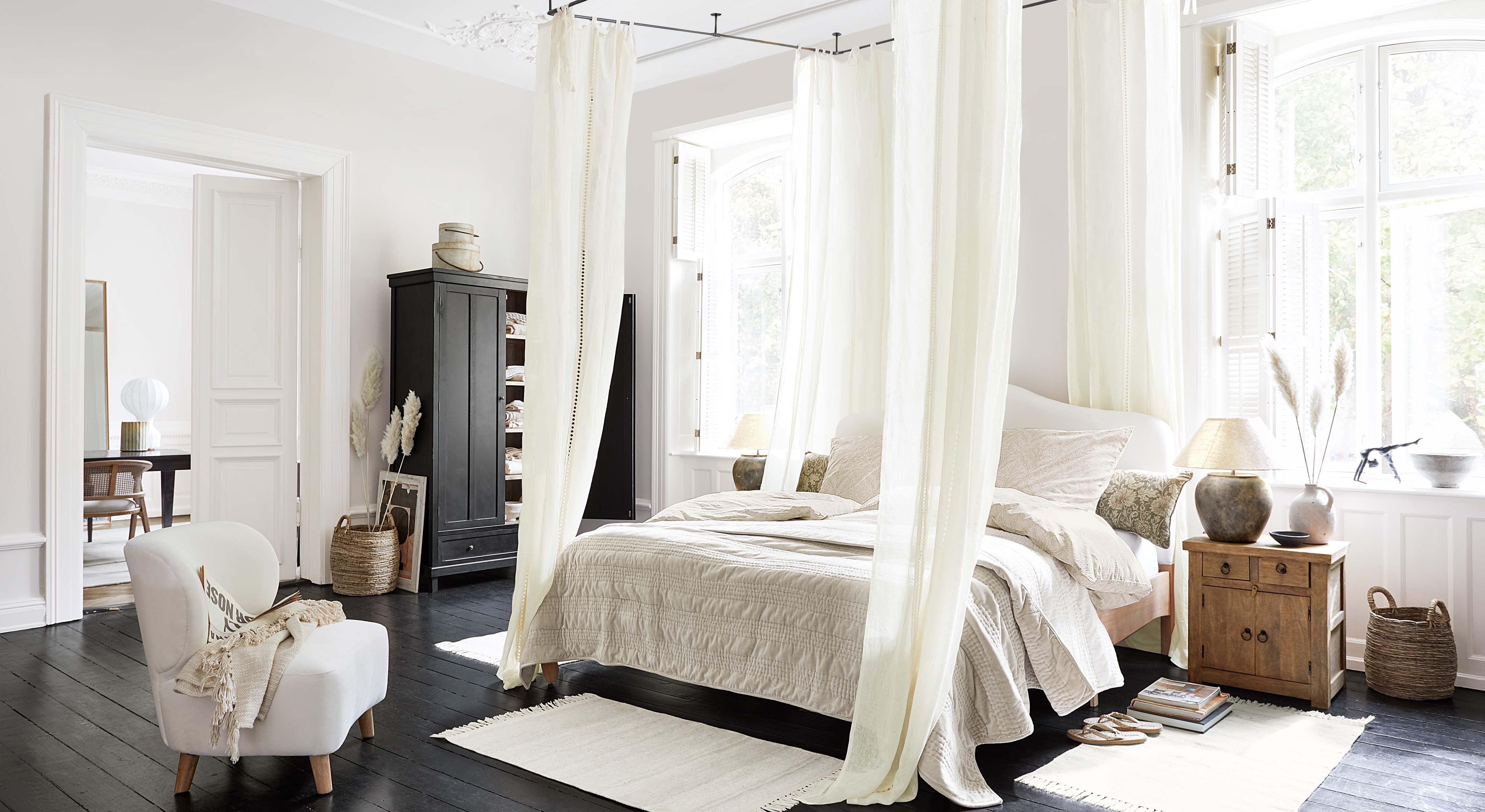 Chambre chaleureuse avec lit à baldaquin, literie beige clair et meubles en bois de style scandinave