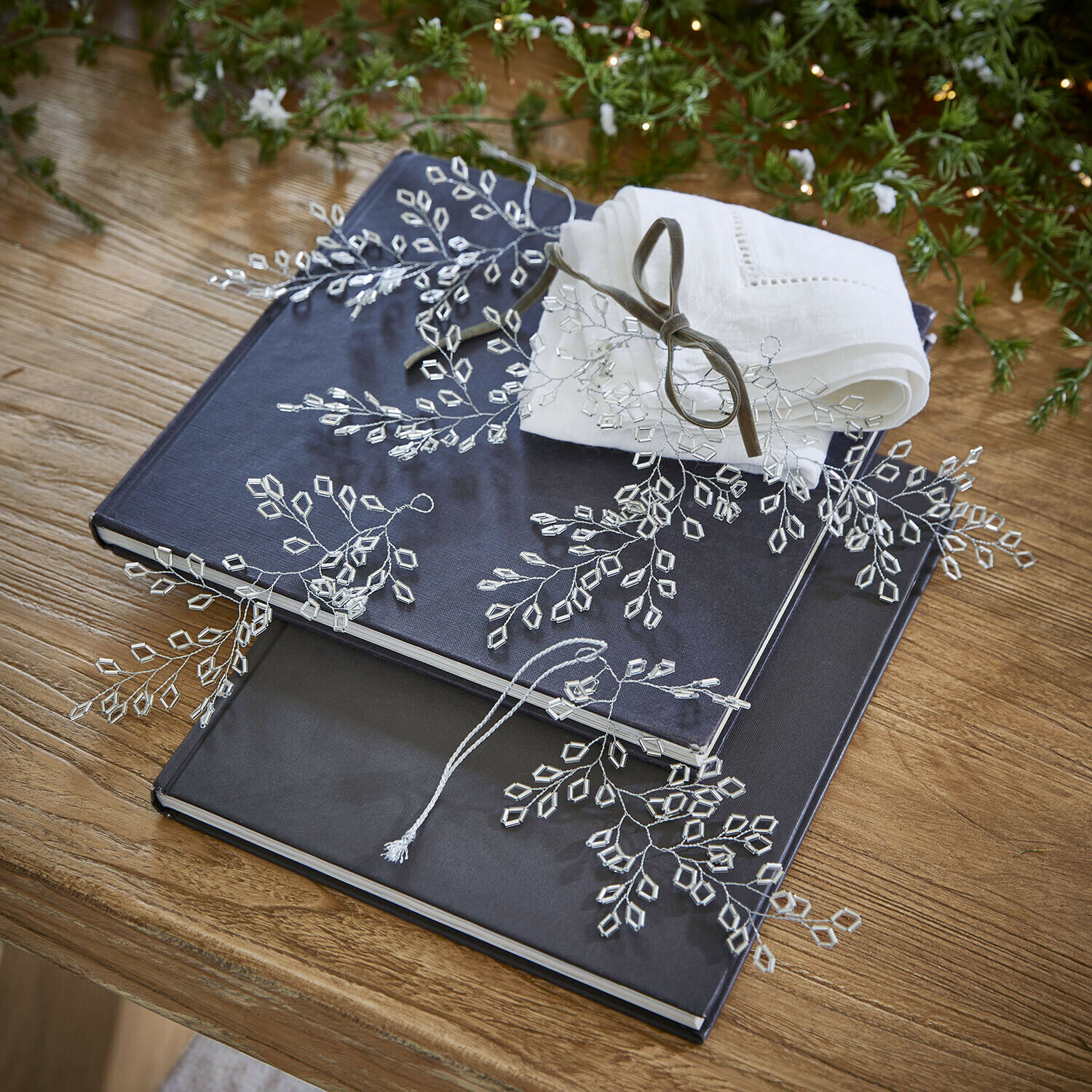 Lot de 6 décorations Alruna Deux albums bleu marine et noir sur une table en bois avec une serviette en lin blanc et décoration en cristal