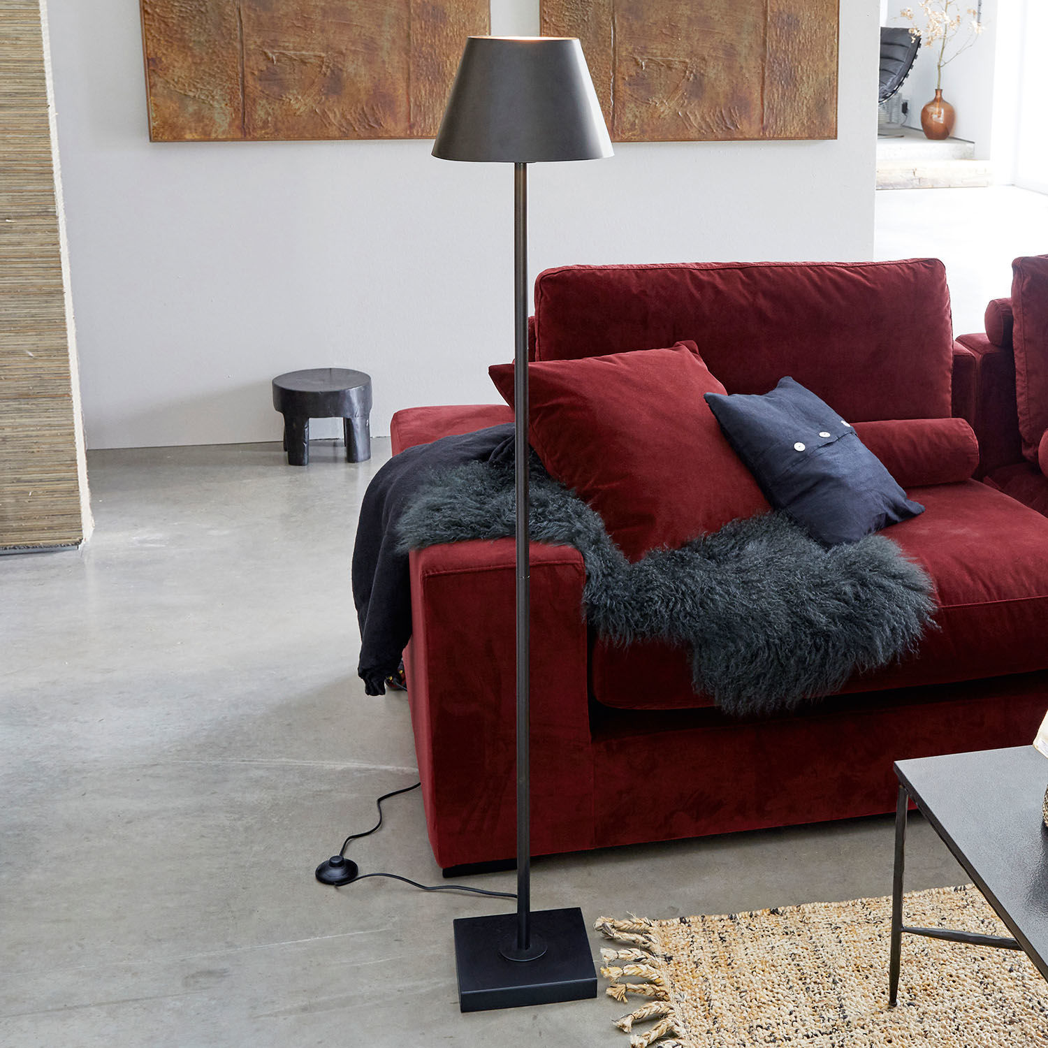 Lampadaire Marjan Lampadaire noir en métal avec abat-jour à côté d'un canapé rouge et d'un tapis dans un salon moderne
