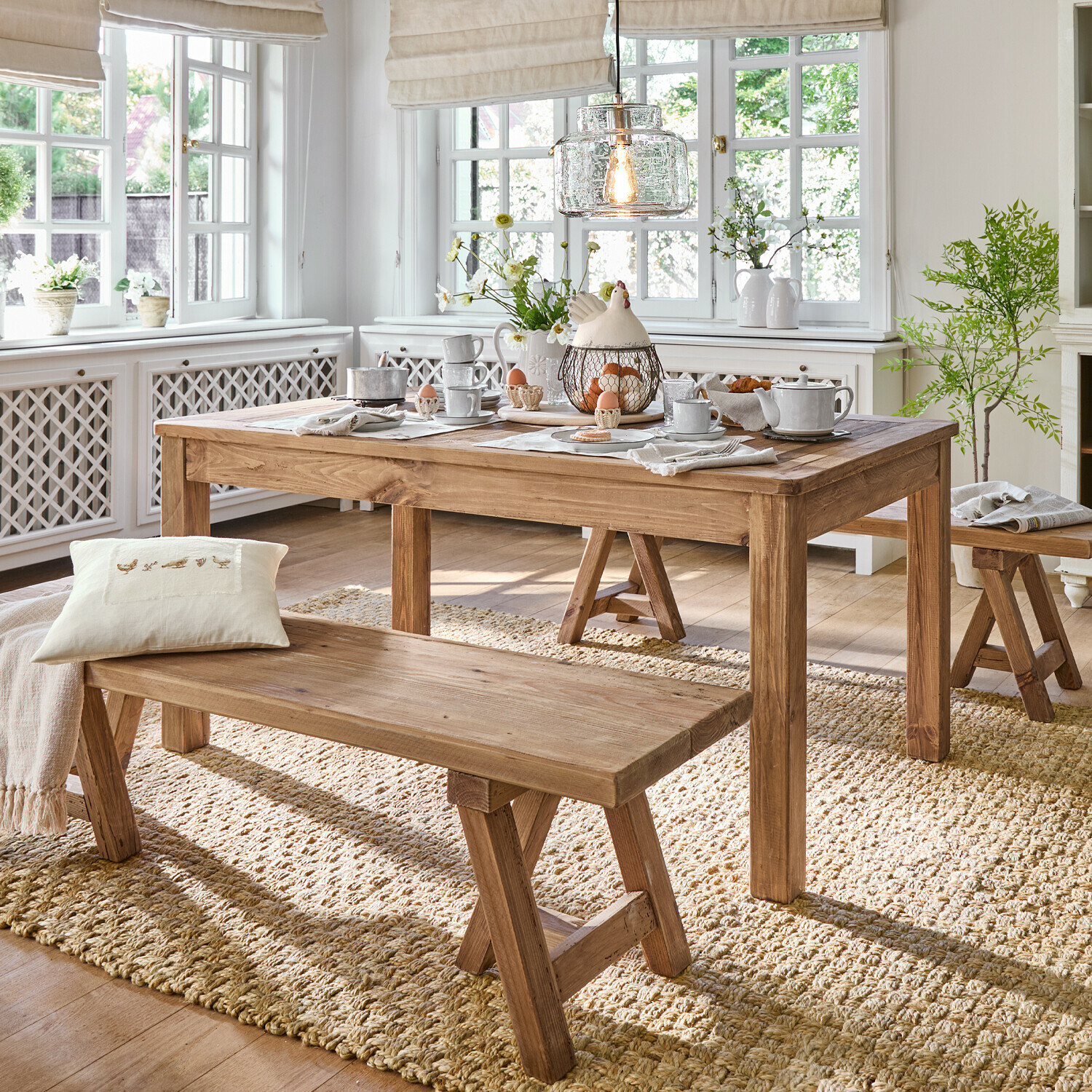 Table Amherst Salle à manger avec table et bancs en bois sur tapis naturel, intérieur lumineux avec décorations et lumière
