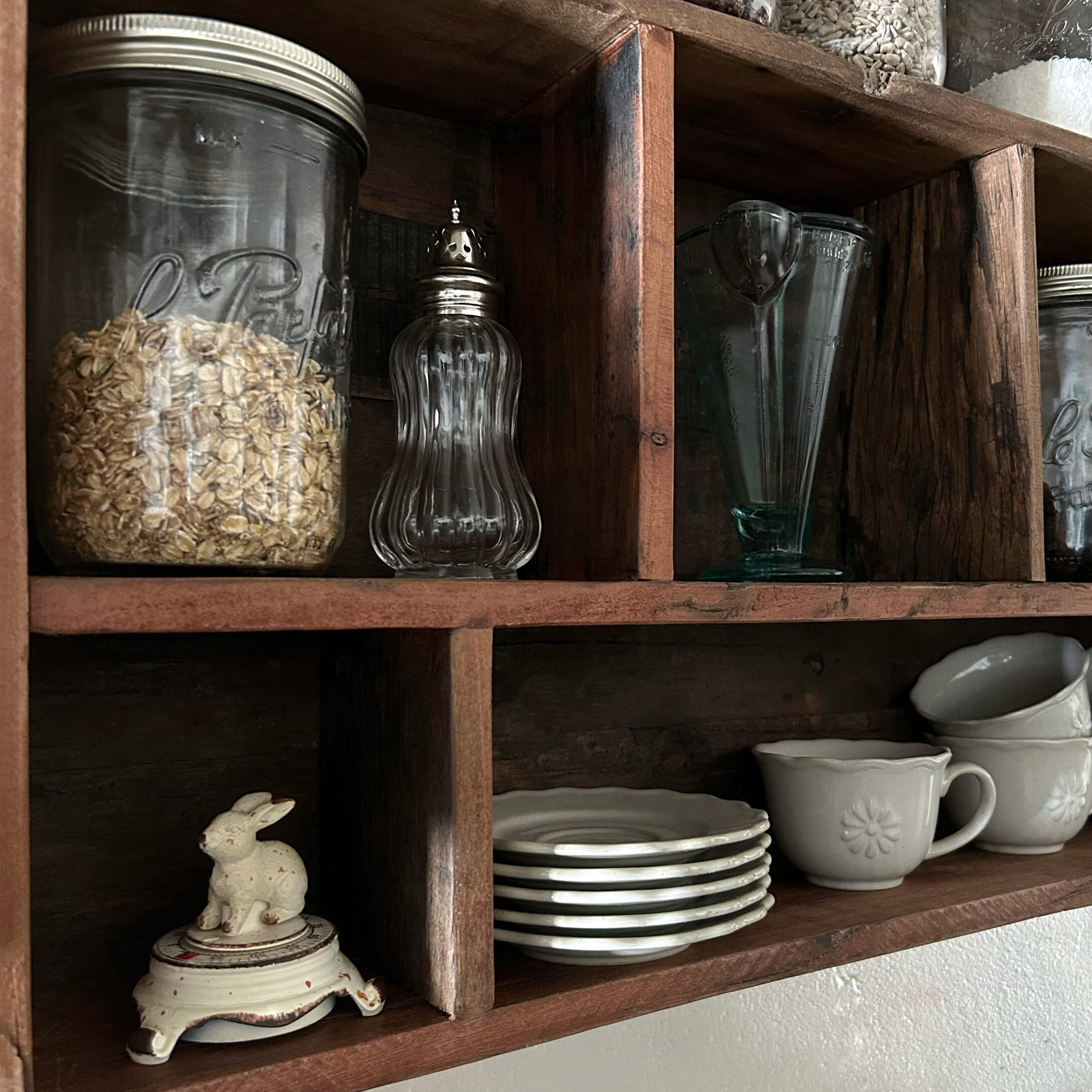 Étagère en bois avec bocaux en verre transparents et vaisselle blanche en céramique