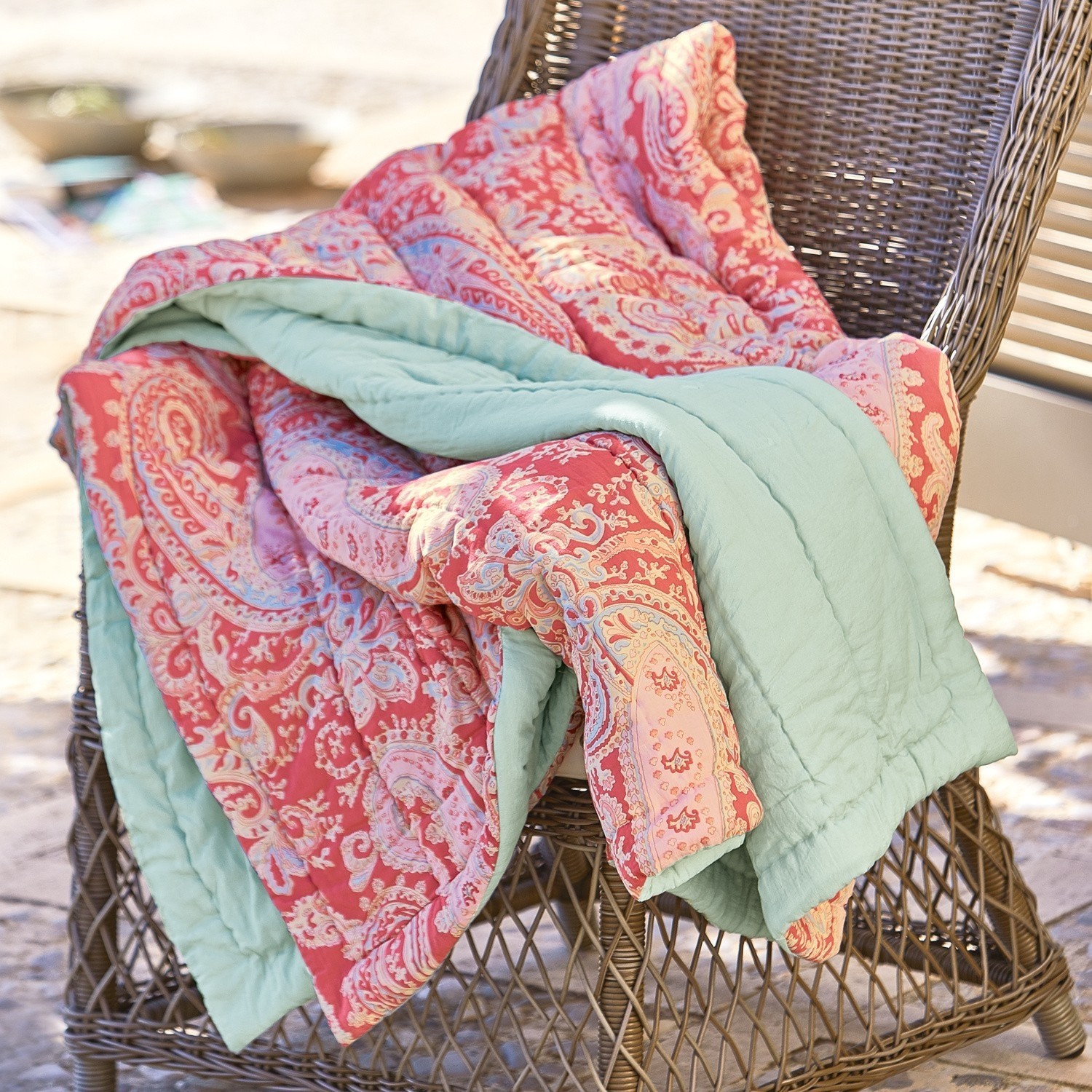 Plaid Aram Plaid réversible rouge à motif paisley avec doublure verte douce sur une chaise en osier
