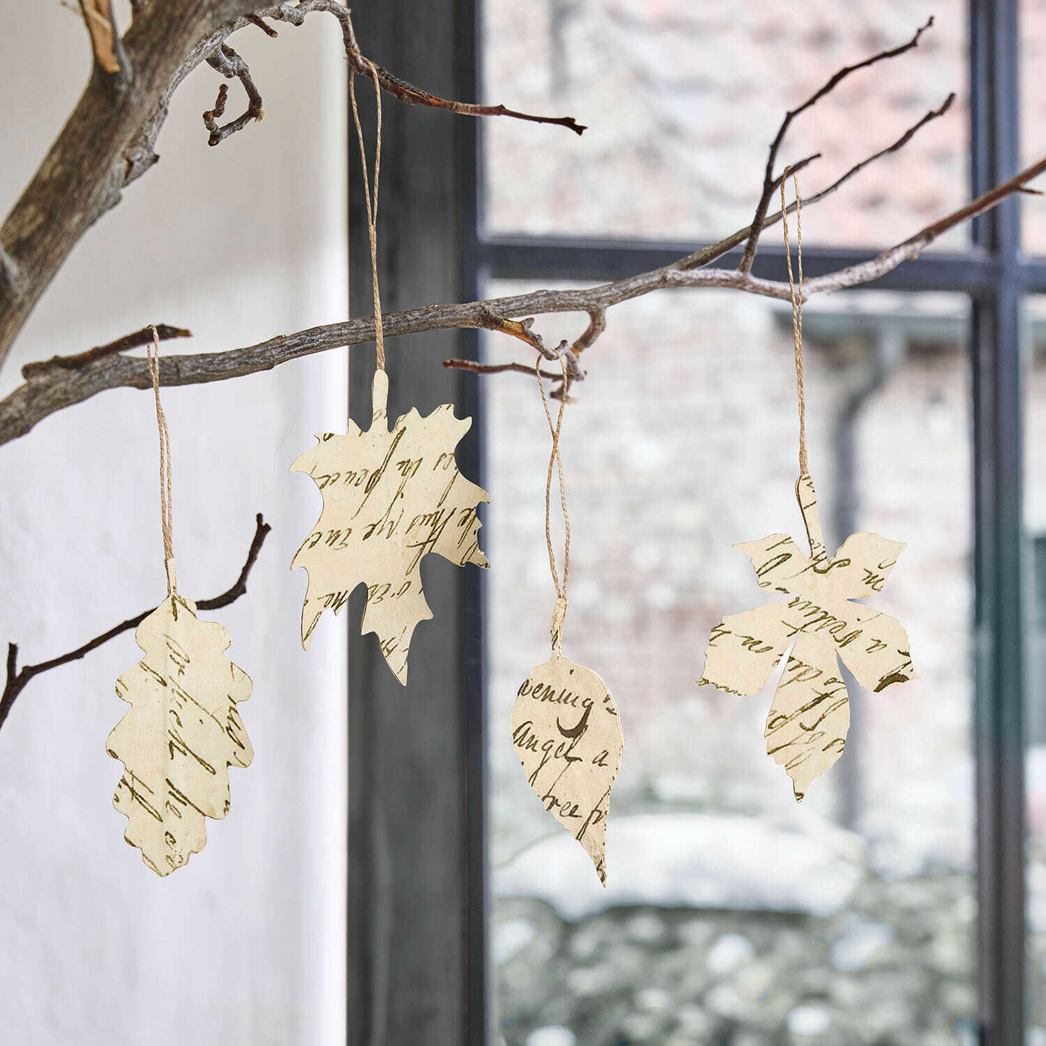 Lot de 4 décorations à suspendre Fleuriene Décorations en forme de feuilles en papier avec écriture suspendues à une branche devant une fenêtre