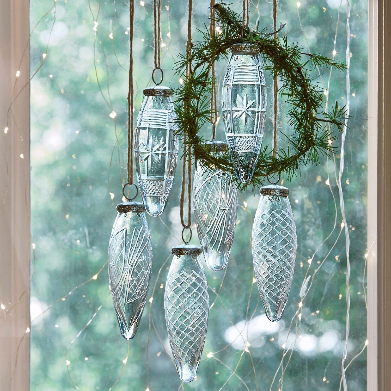 Lot de 6 décorations de Noël Loulay Décorations de Noël en verre transparent avec motifs suspendues à des cordes devant une fenêtre éclairée par des guirlandes LED
