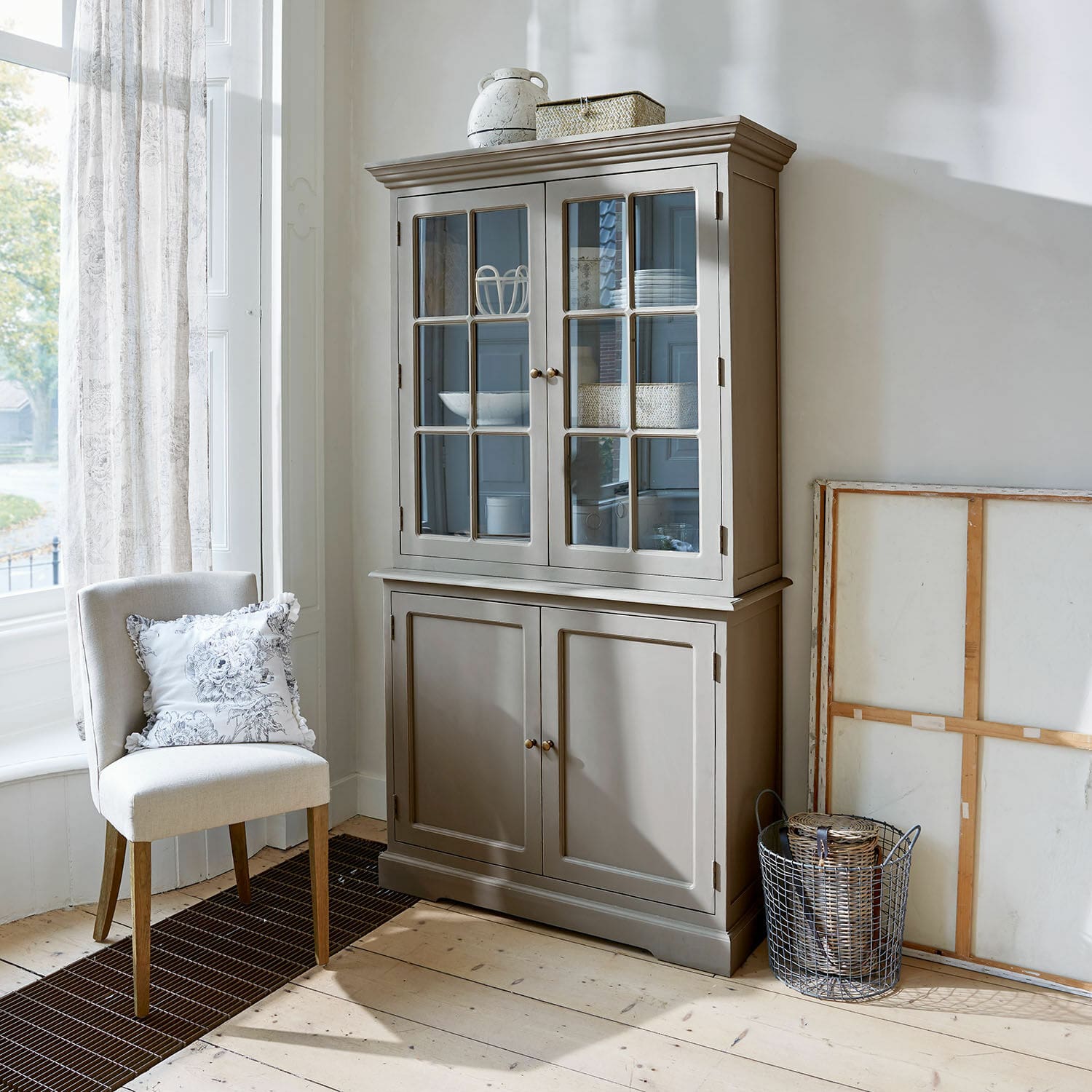 Vaisselier Rosebrook Vitrine en bois grise avec portes vitrées et étagères dans un salon lumineux