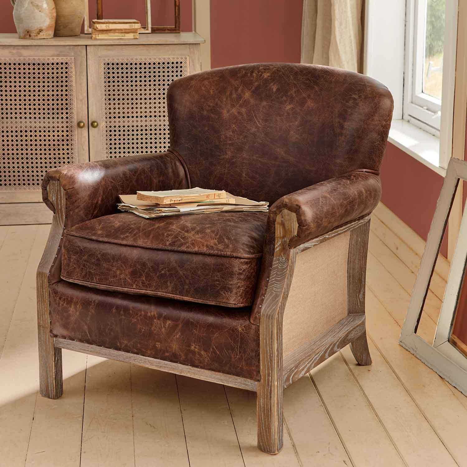 Fauteuil en cuir marron vieilli avec cadre en bois dans un intérieur rustique avec livres