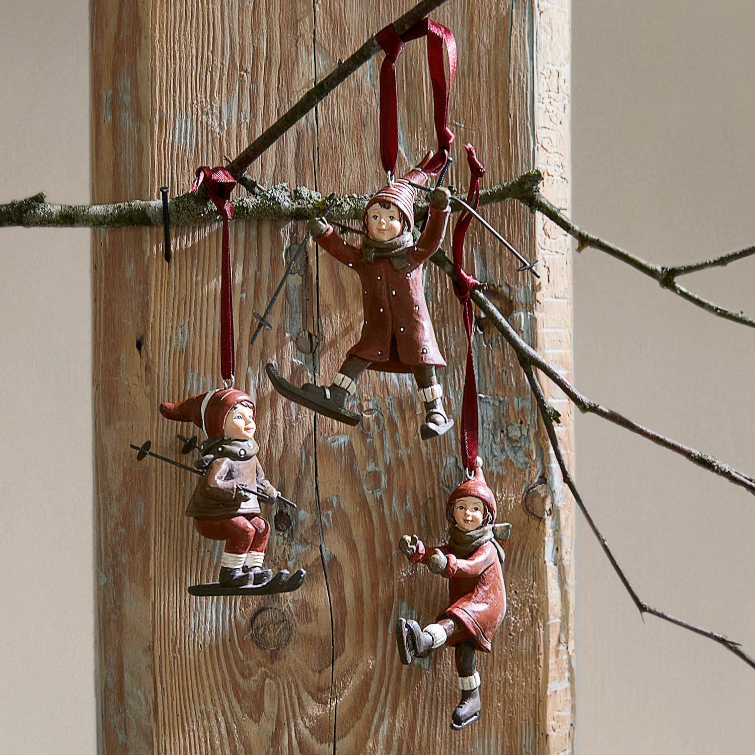 Lot de 3 décorations à suspendre Bibury Trois décorations rouges d'enfants en ski et patinage suspendues sur fond en bois, décoration hivernale