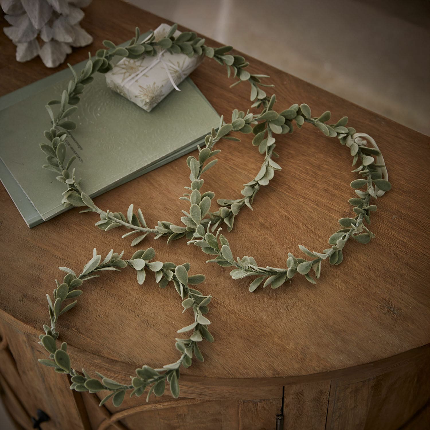 Lot de 3 couronnes Carivela Couronnes décoratives vertes en feuilles douces posées sur une table en bois, décoration naturelle