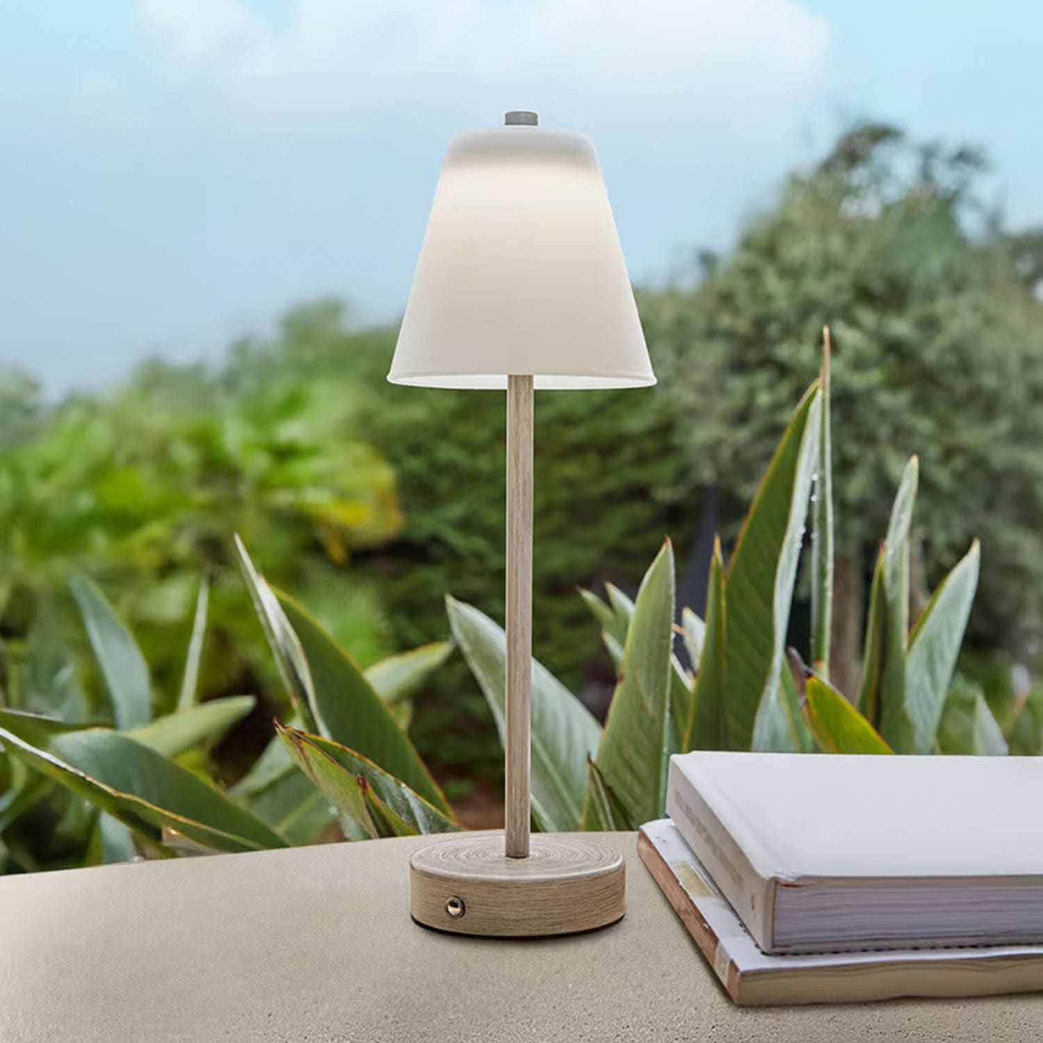 Lampe de table en bois clair avec abat-jour blanc devant des plantes vertes, décoration intérieure