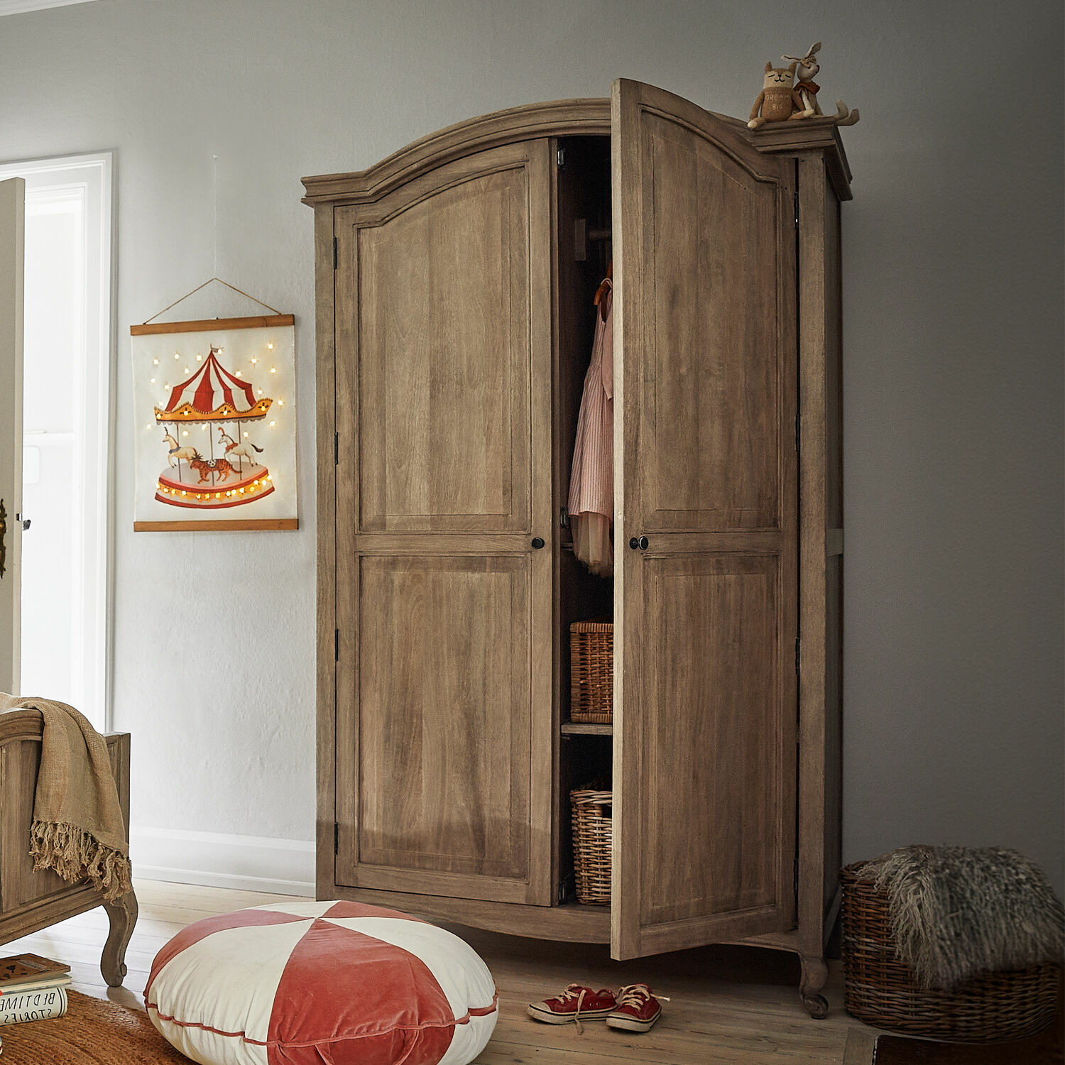 Armoire Éveilou Armoire en bois naturel avec portes ouvertes, paniers en osier et décorations dans une chambre d'enfant