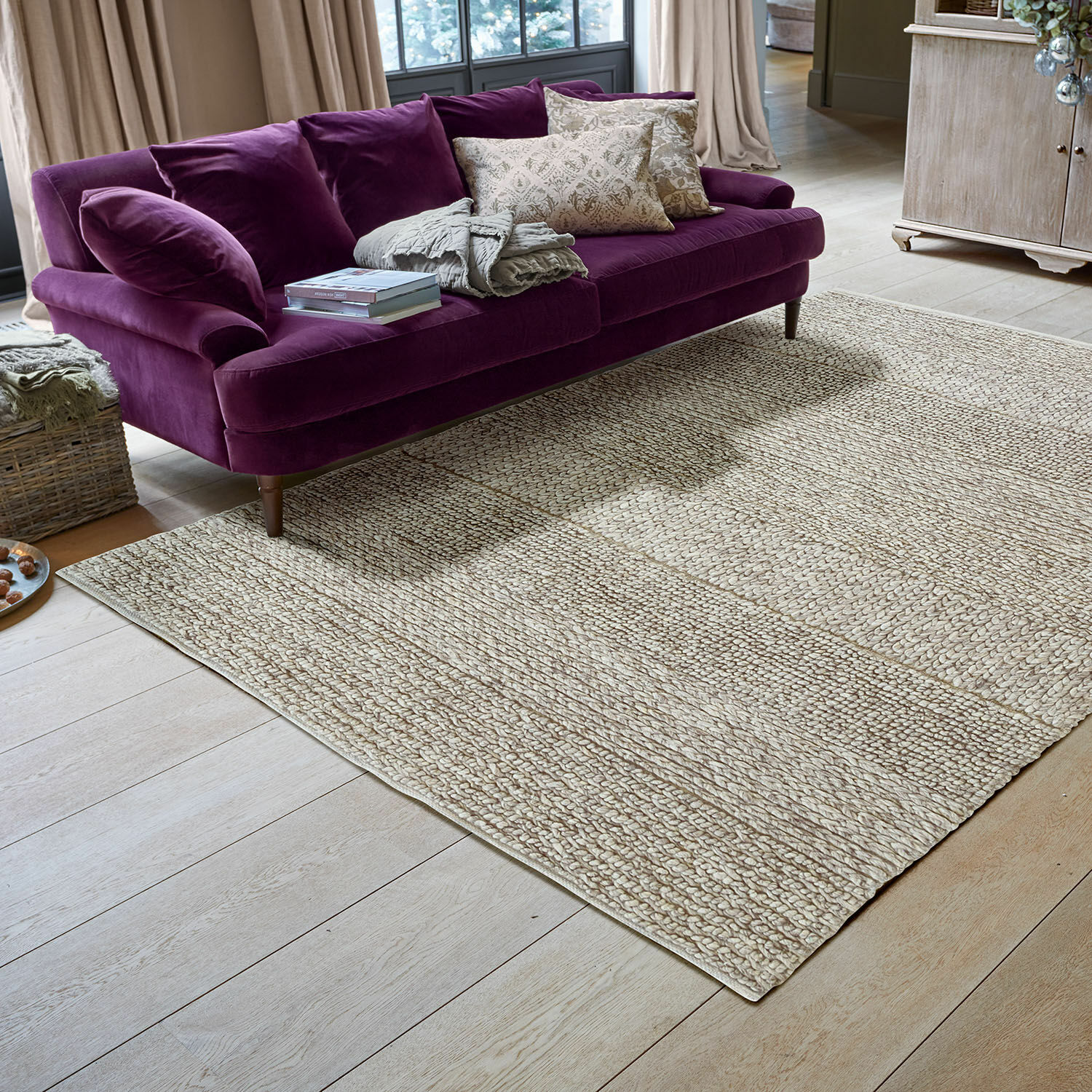 Tapis Welezas Tapis beige en matériau naturel tressé dans un salon moderne avec un canapé violet