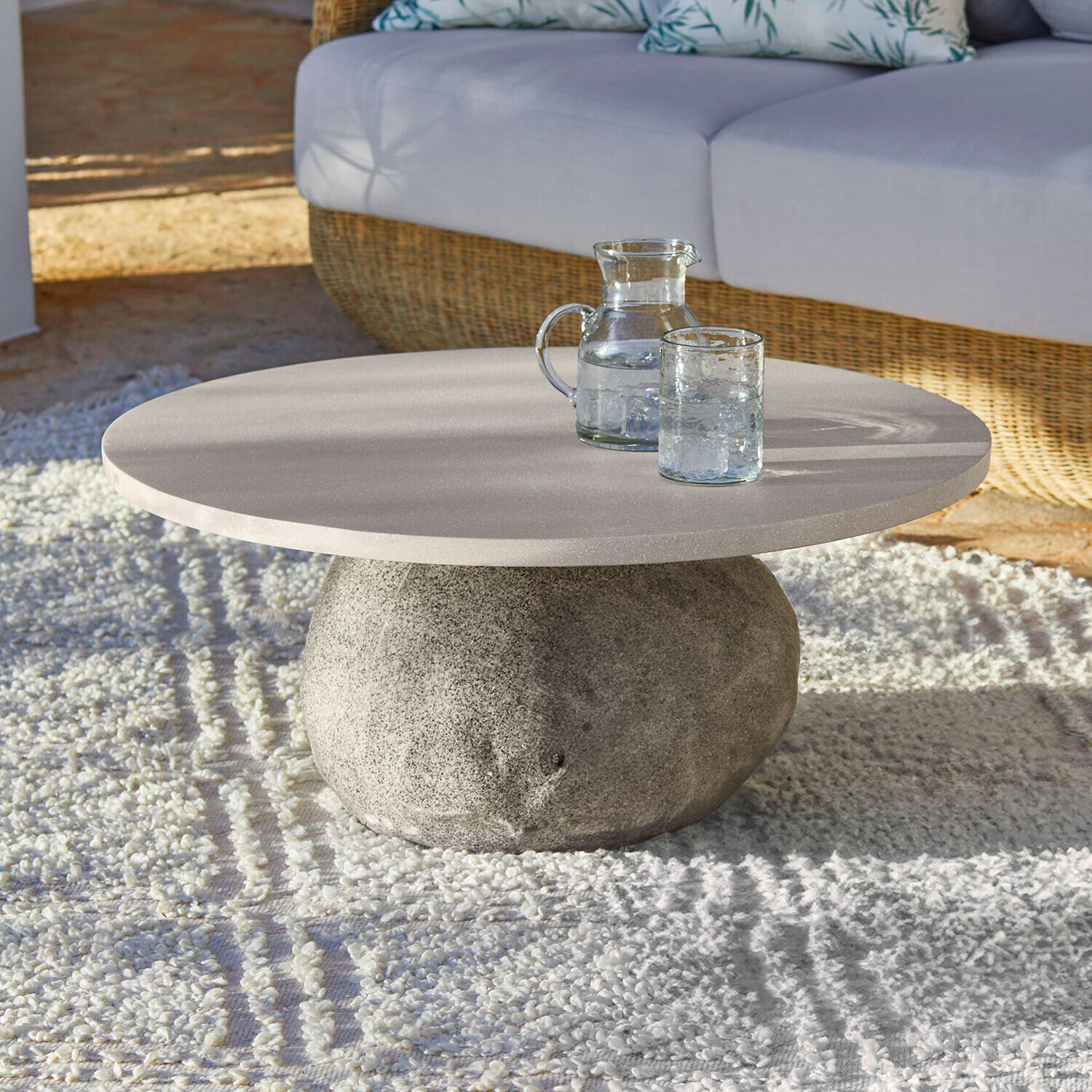 Table basse Orivana Table basse ronde avec base en pierre et plateau clair sur tapis dans un salon lumineux