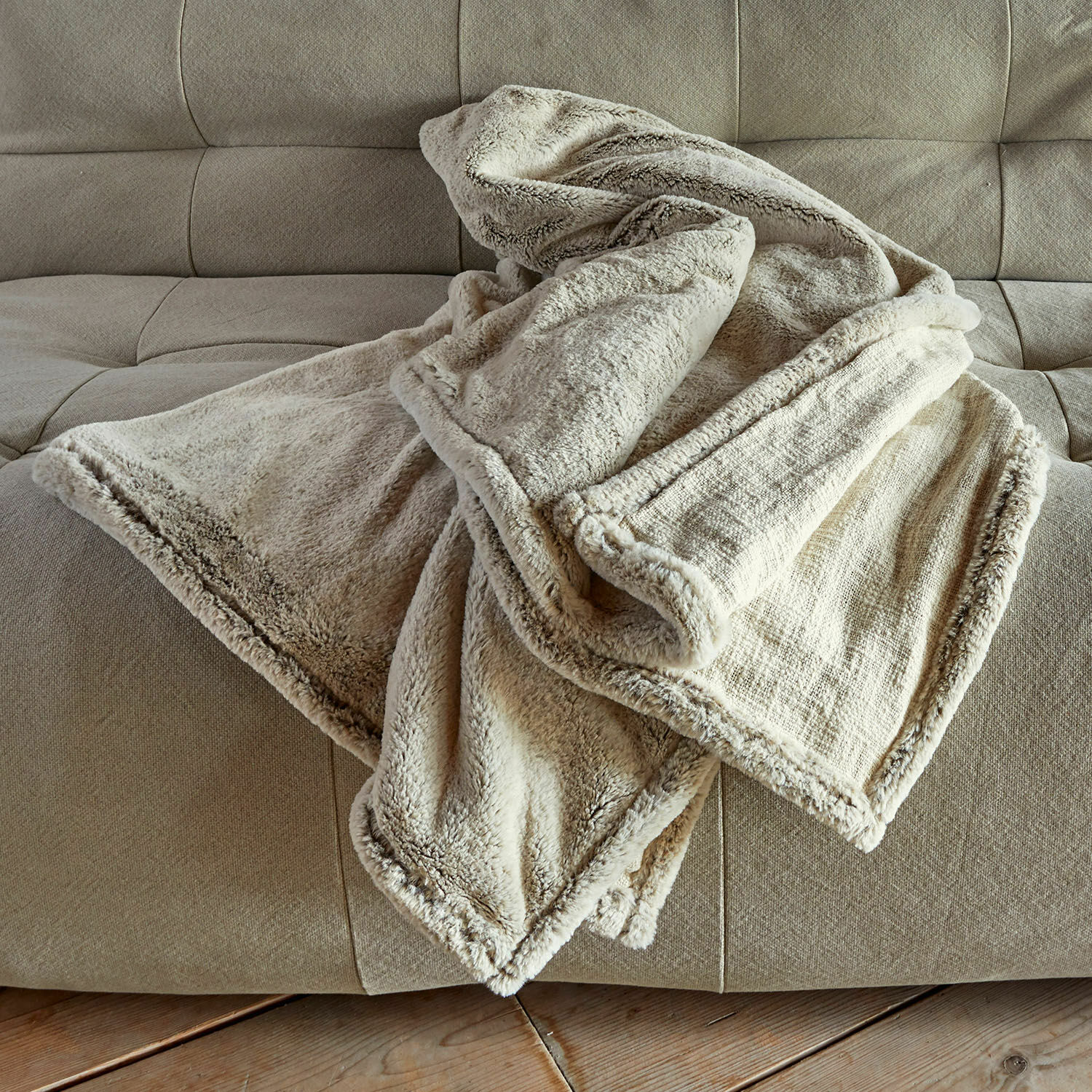 Plaid Newman Plaid doux crème avec bordure en fausse fourrure sur un canapé beige, parfait pour un intérieur cosy