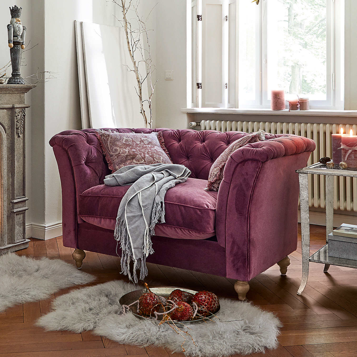 Canapé deux places en velours violet avec coussins capitonnés et plaid gris dans un salon chaleureux