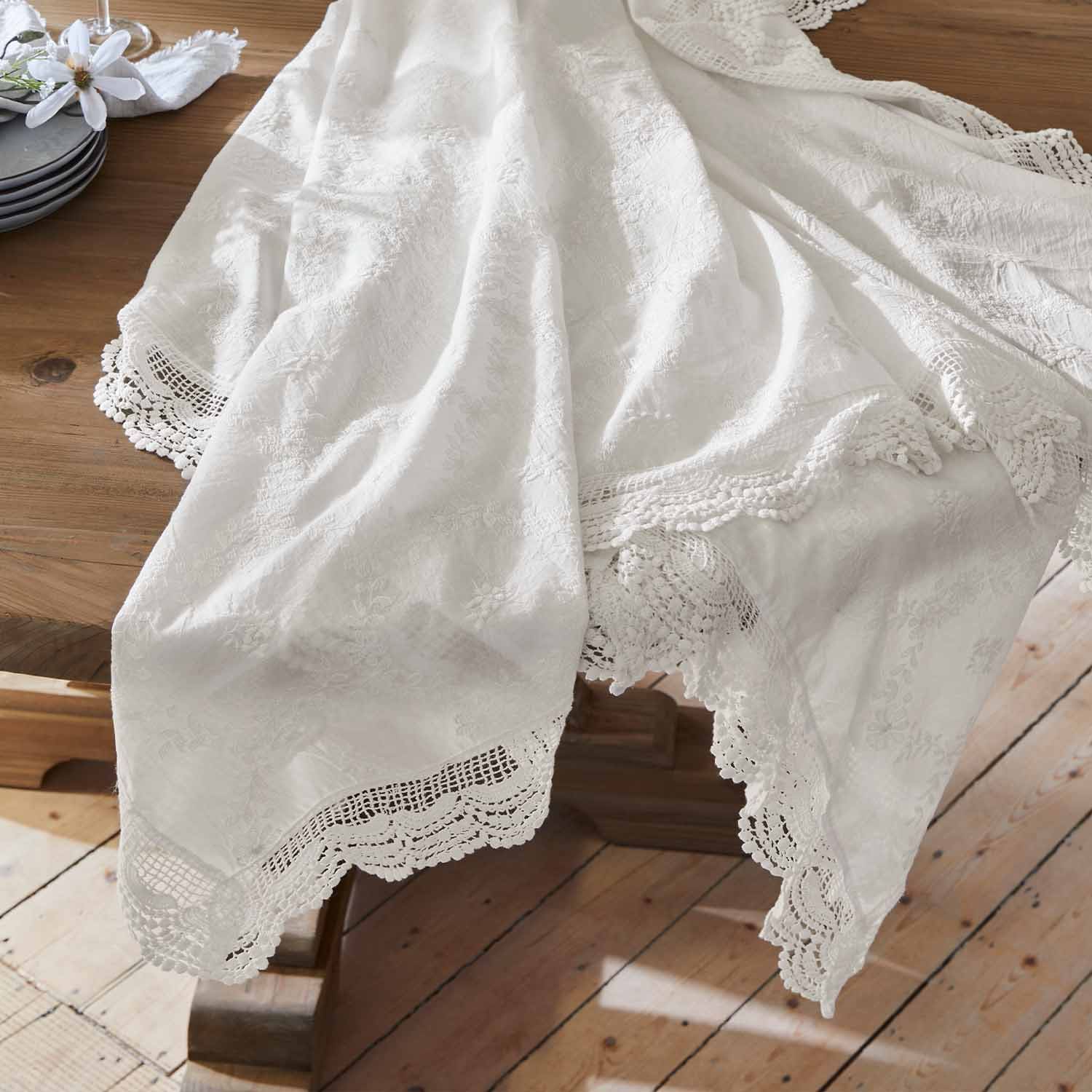 Nappe blanche en tissu brodé avec bordure en dentelle sur une table en bois, décoration de table