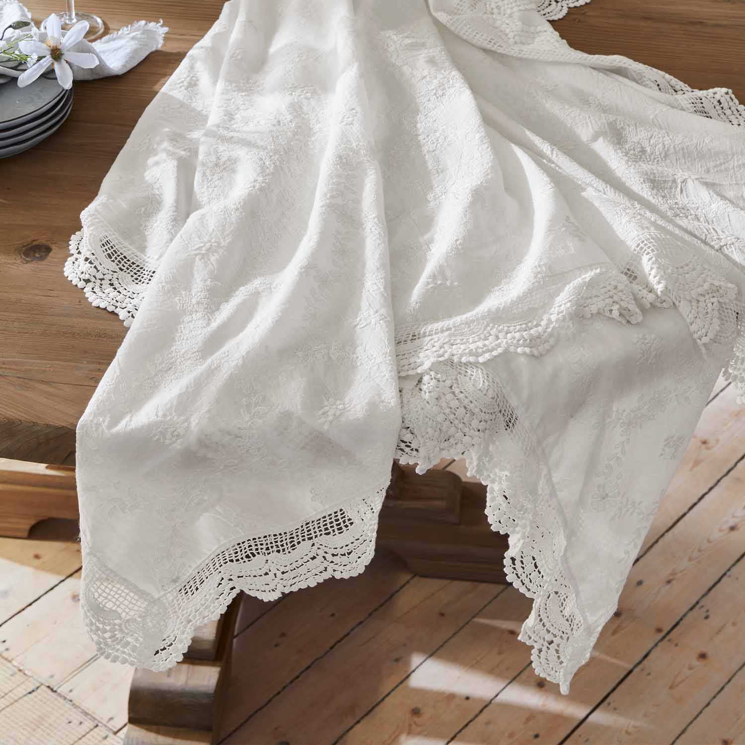 Nappe blanche en tissu brodé avec bordure en dentelle sur une table en bois, décoration de table