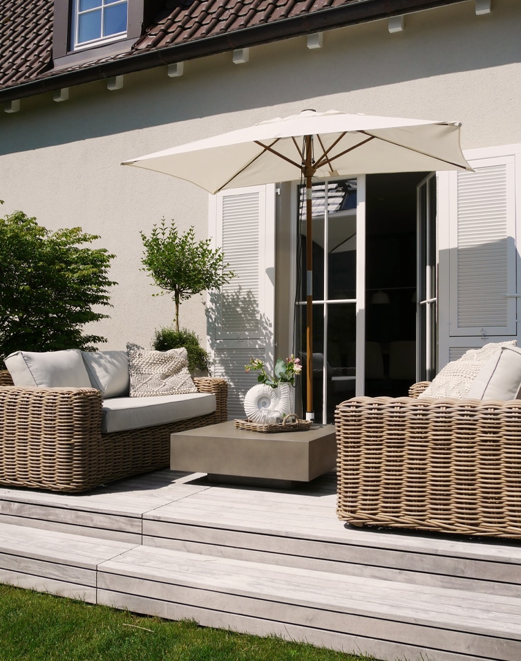 Ensemble de mobilier de jardin en rotin beige avec parasol et coussins sur terrasse en bois clair