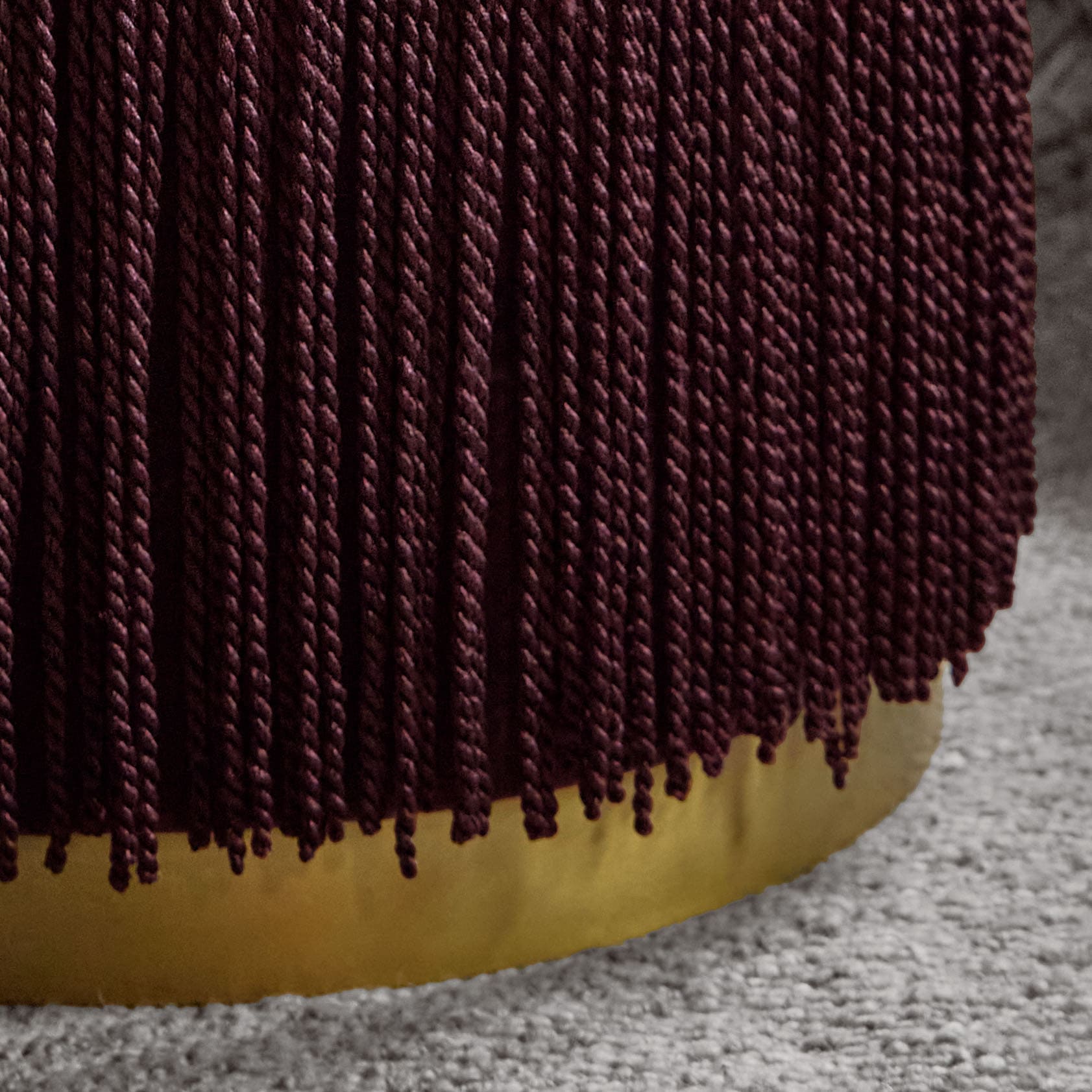 Matériau torsadé bordeaux sur fond jaune posé sur un tapis gris, texture textile décorative