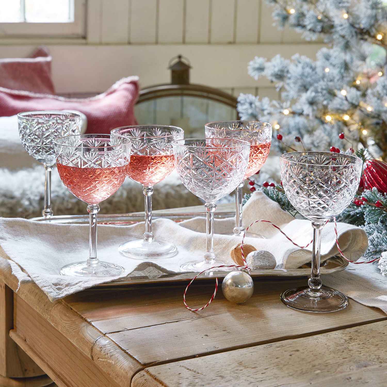 Lot de 6 coupes Olite Ensemble de six verres à vin en cristal avec motif gravé, certains remplis de vin rosé, décor festif