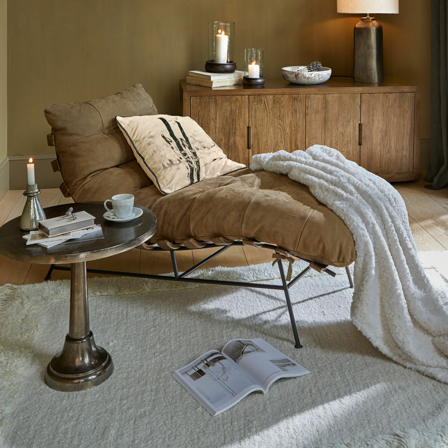Méridienne Horraine Fauteuil en cuir marron avec couverture blanche et coussin, près d'un buffet en bois et d'une table basse