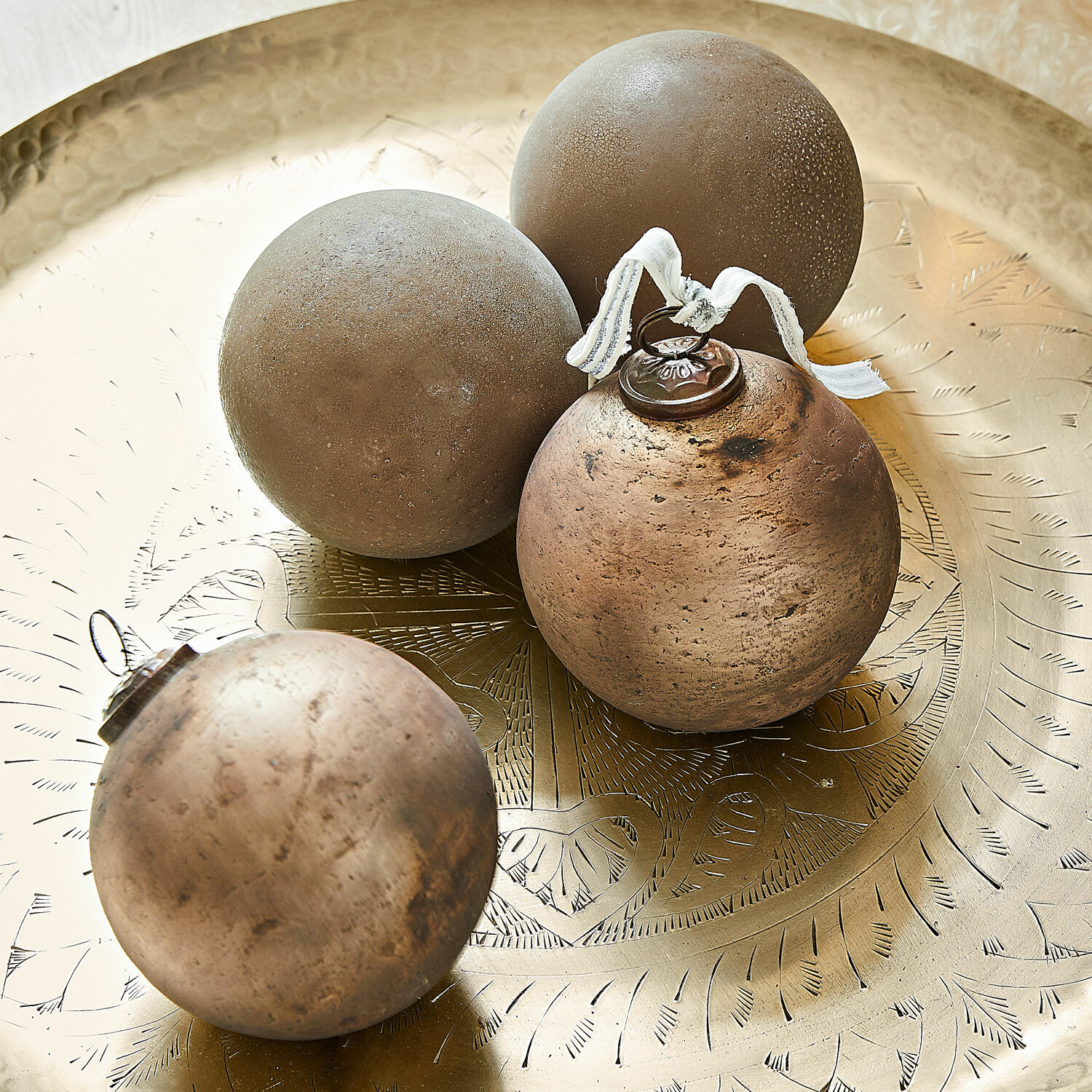 Lot de 4 boules de Noël Ophraine Quatre boules décoratives marron posées sur un plateau en laiton gravé avec motifs délicats