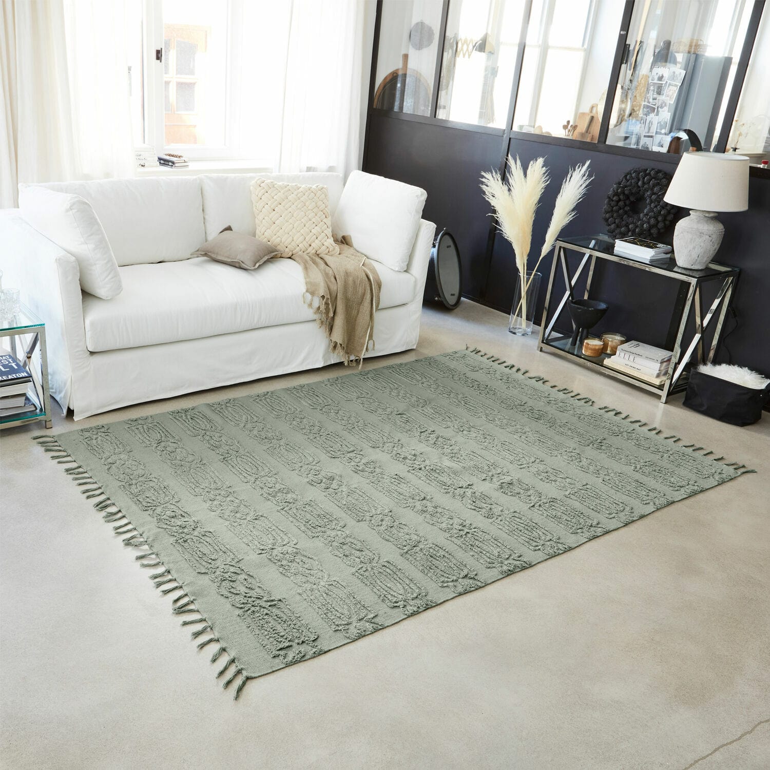 Tapis vert en coton avec motif texturé et franges dans un salon moderne avec canapé blanc