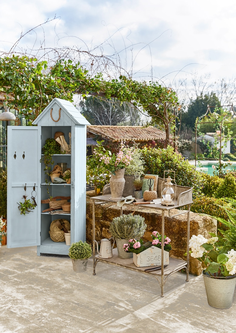 Armoire de jardin en bois bleu avec étagères et table en métal avec fleurs et outils de jardinage
