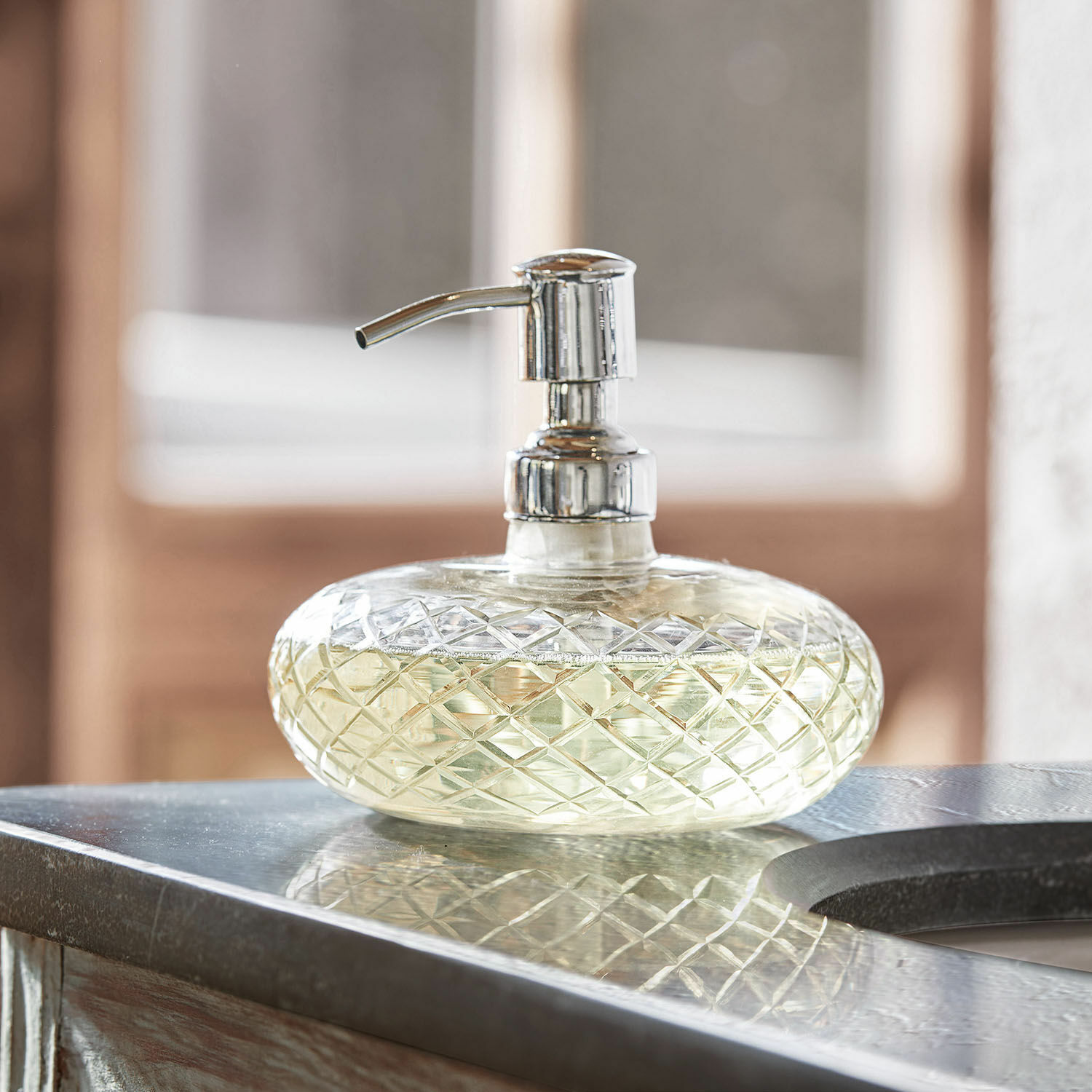 Distributeur de savon Cullen Distributeur de savon en verre avec pompe métallique sur un comptoir, transparent avec liquide jaune clair