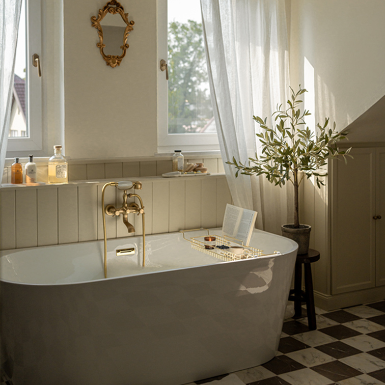 Baignoire autoportante blanche avec robinetterie en laiton et miroir décoratif dans une salle de bain lumineuse avec plante