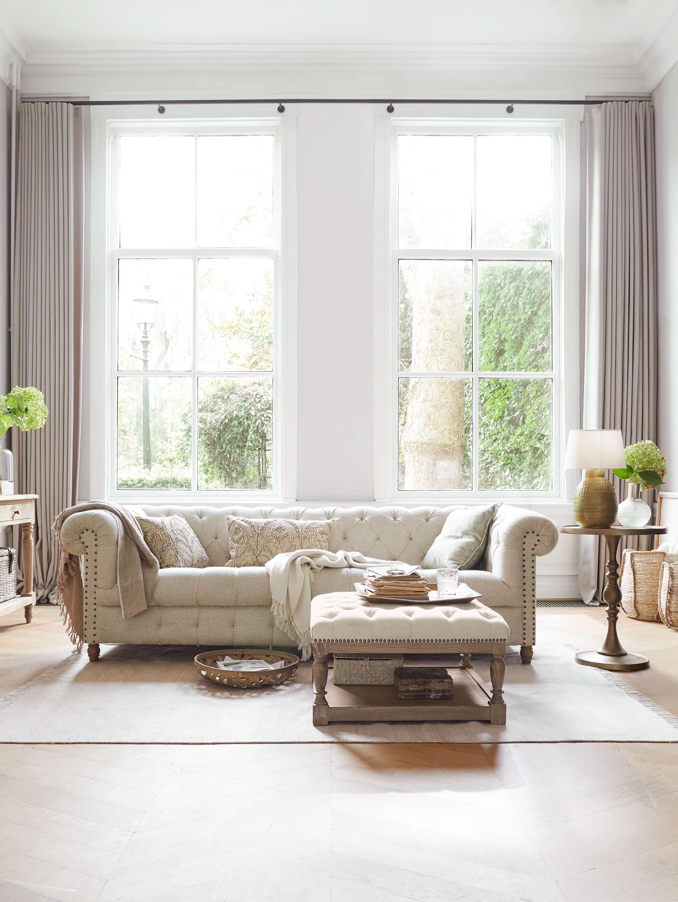 Canapé Chesterfield beige en tissu matelassé dans un salon lumineux avec lumière naturelle