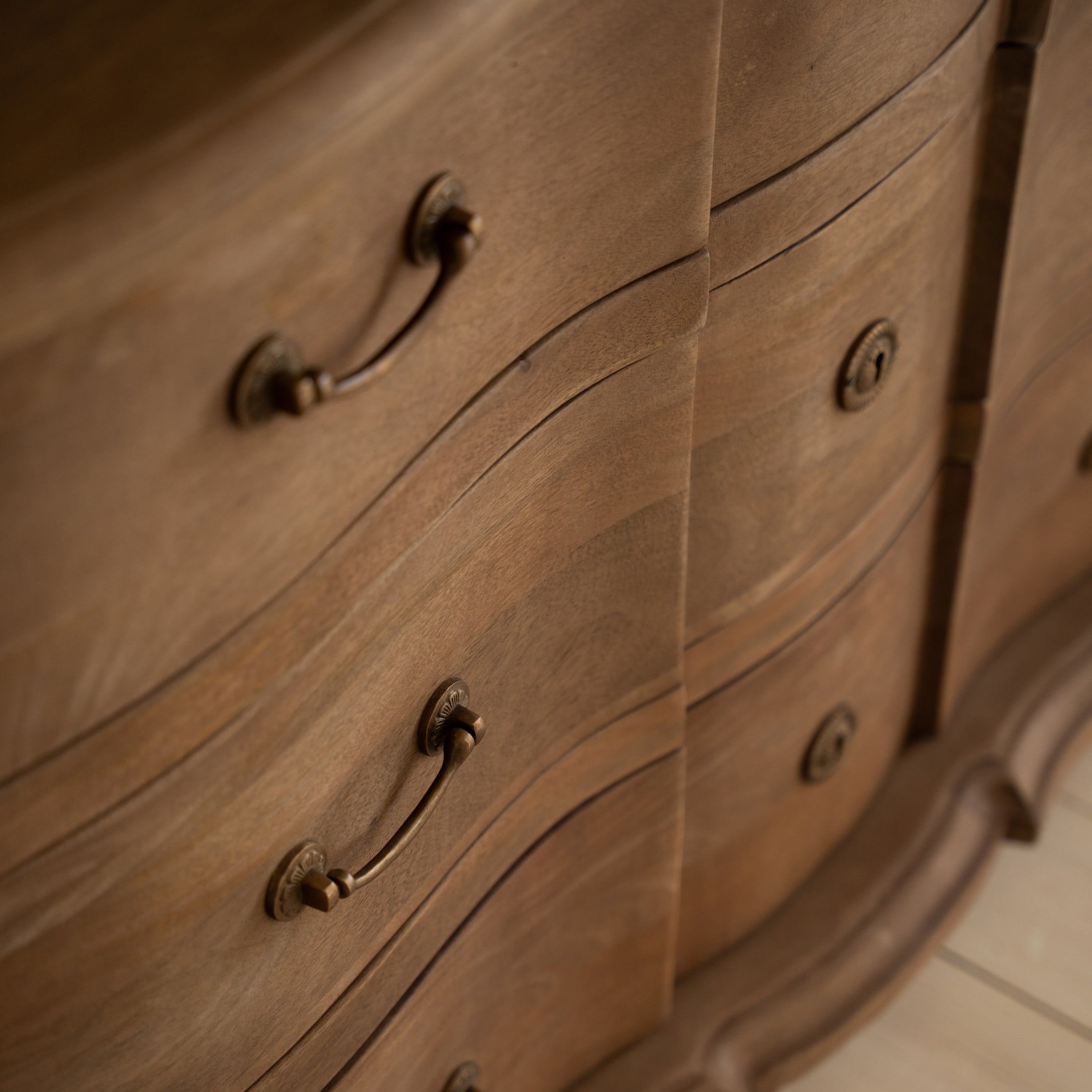 Gros plan sur une commode en bois avec poignées en laiton décoratives et finition naturelle du bois