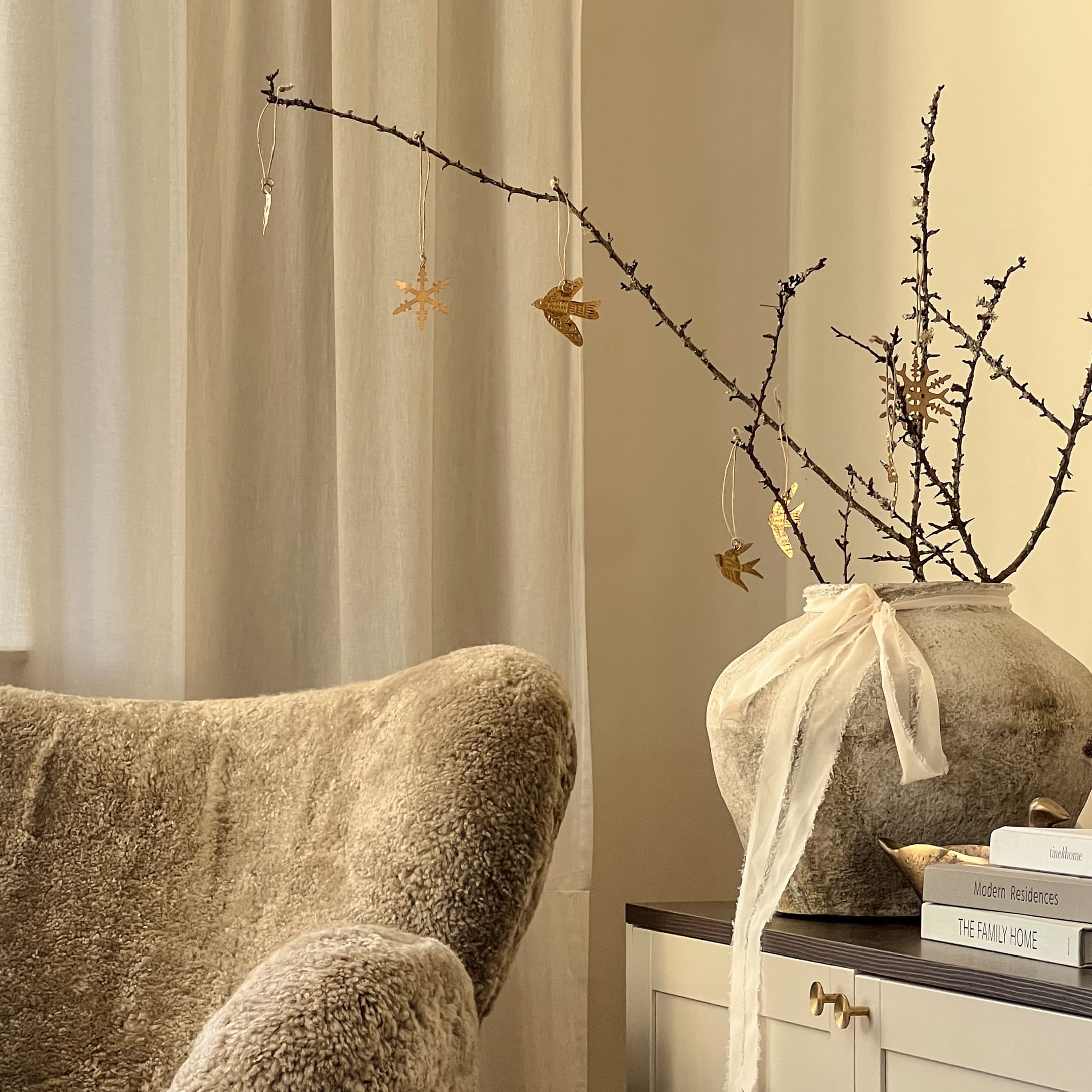 Coin d'hiver douillet avec fauteuil en fausse fourrure beige et vase décoratif avec branches et ornements dorés