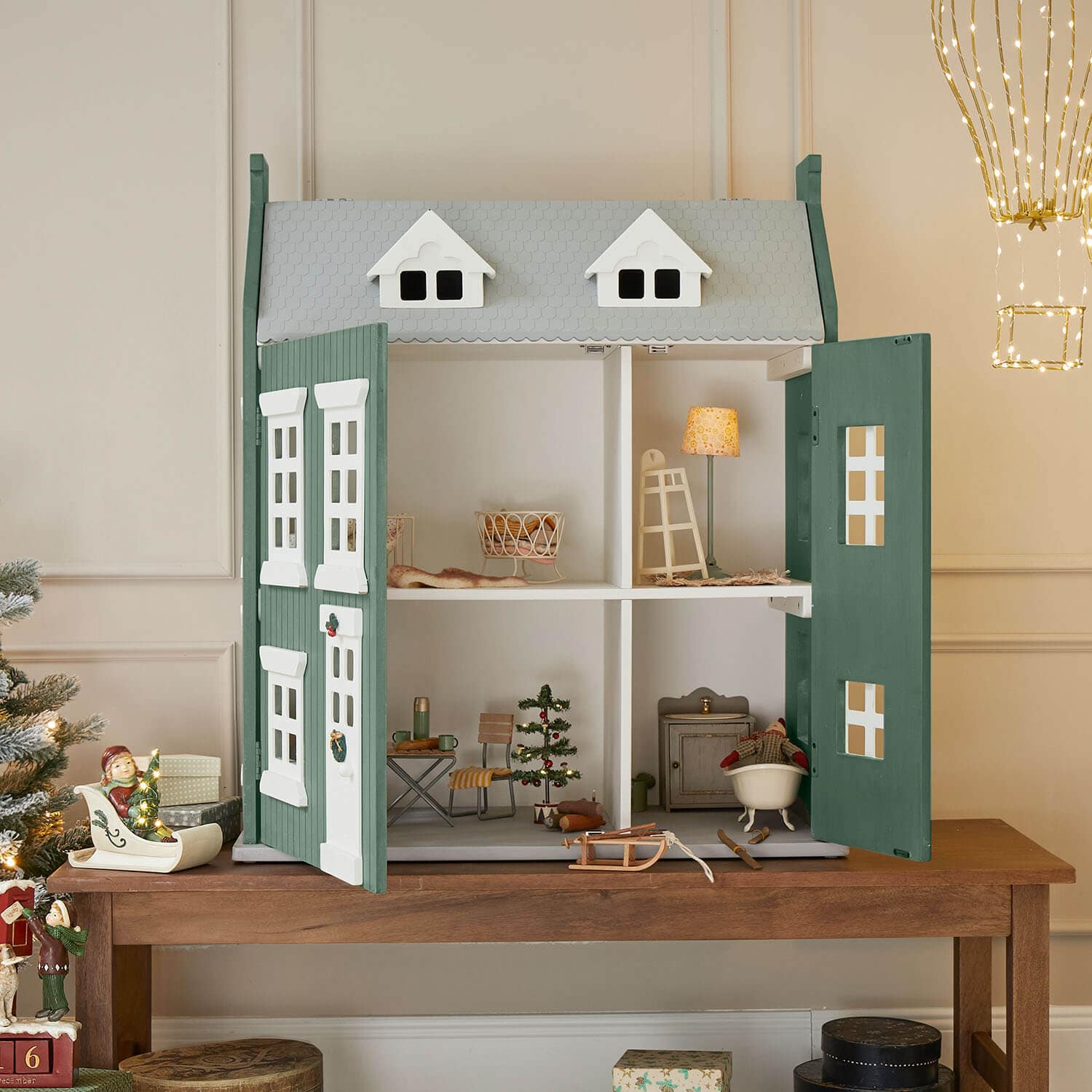Maison de poupée en bois vert et gris avec portes ouvertes et décorations de Noël à l'intérieur