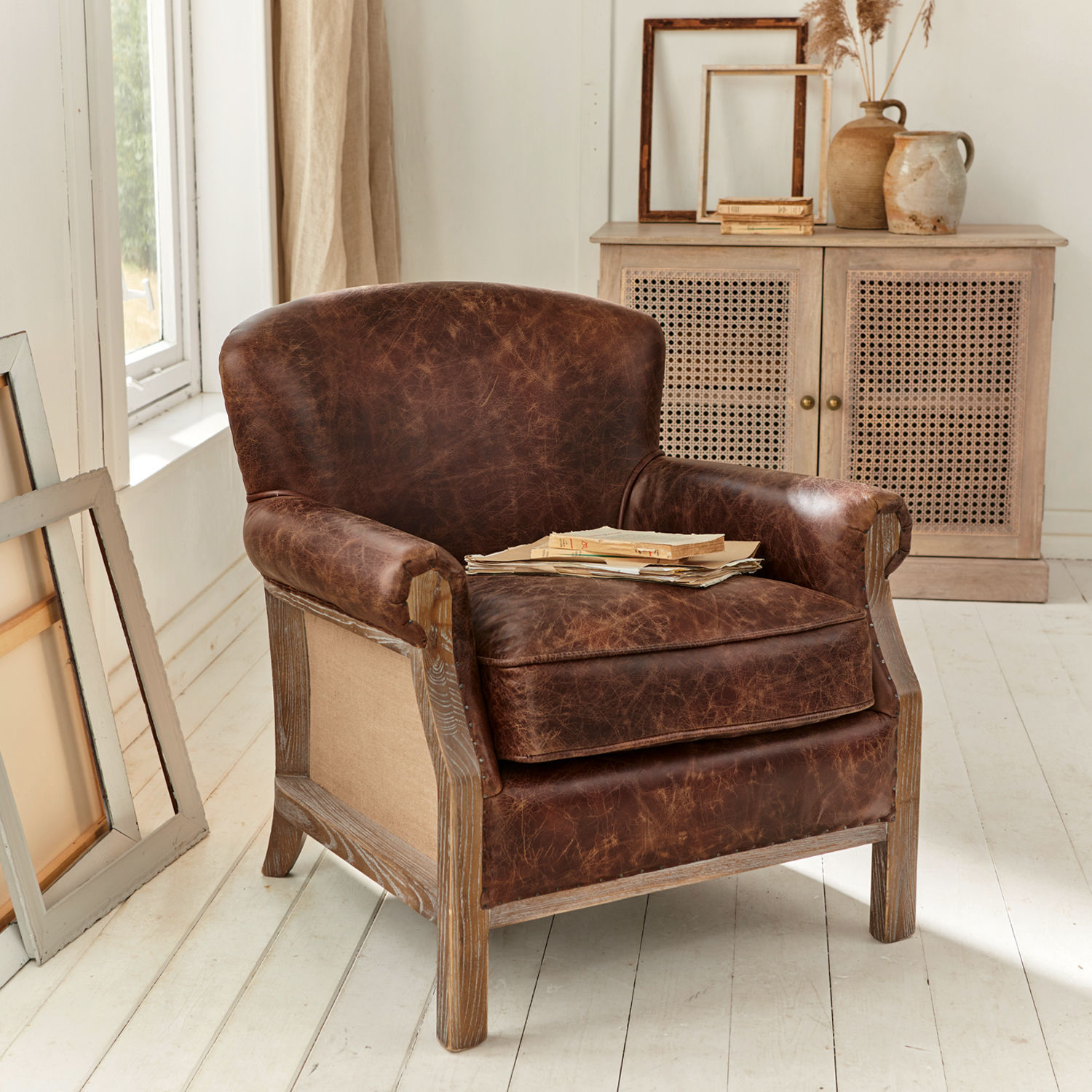 Fauteuil Banbury Fauteuil en cuir marron vieilli avec cadre en bois dans une pièce lumineuse au style naturel