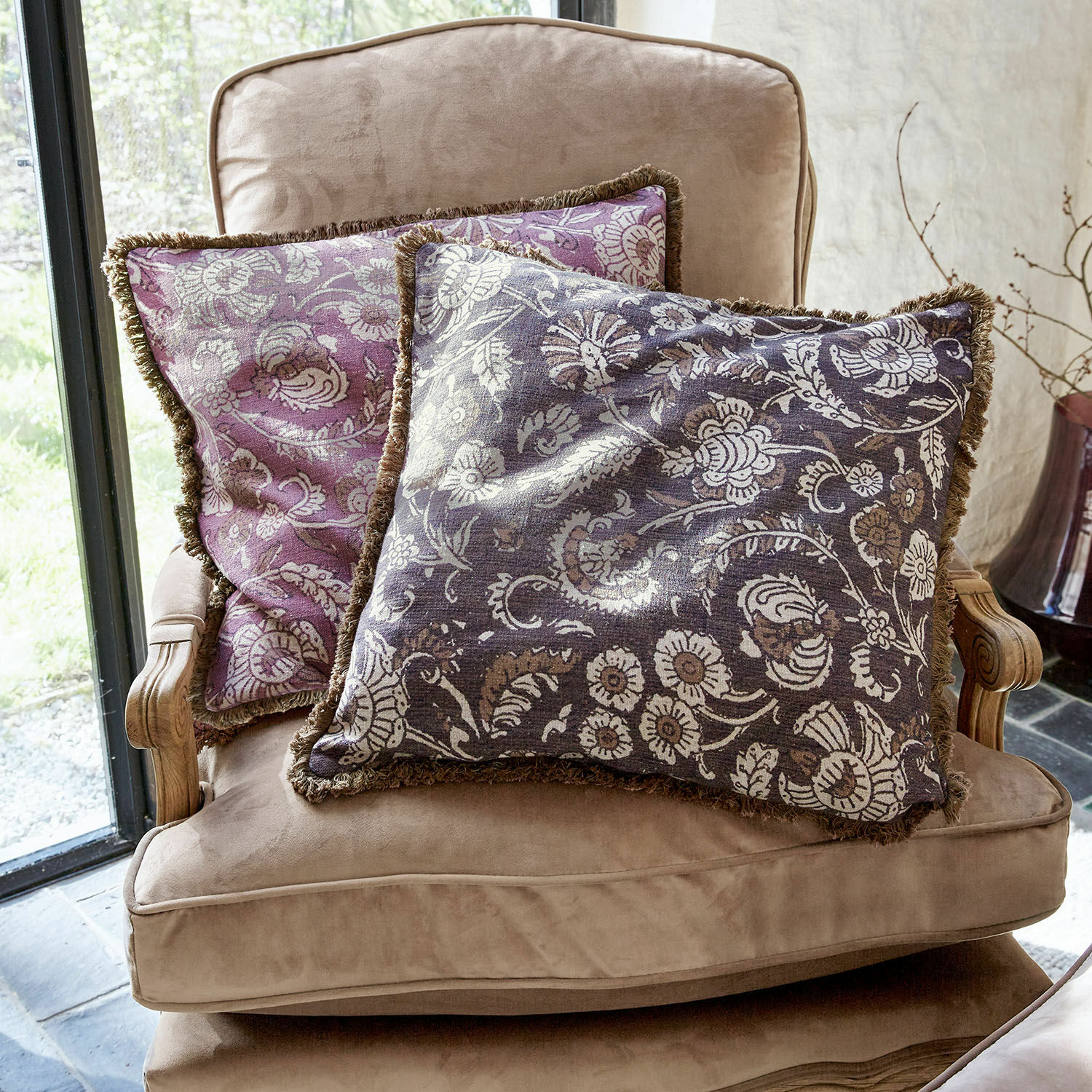Lot de 2 housses de coussins Lalluga Deux coussins décoratifs à motif floral violet et gris sur un fauteuil beige confortable