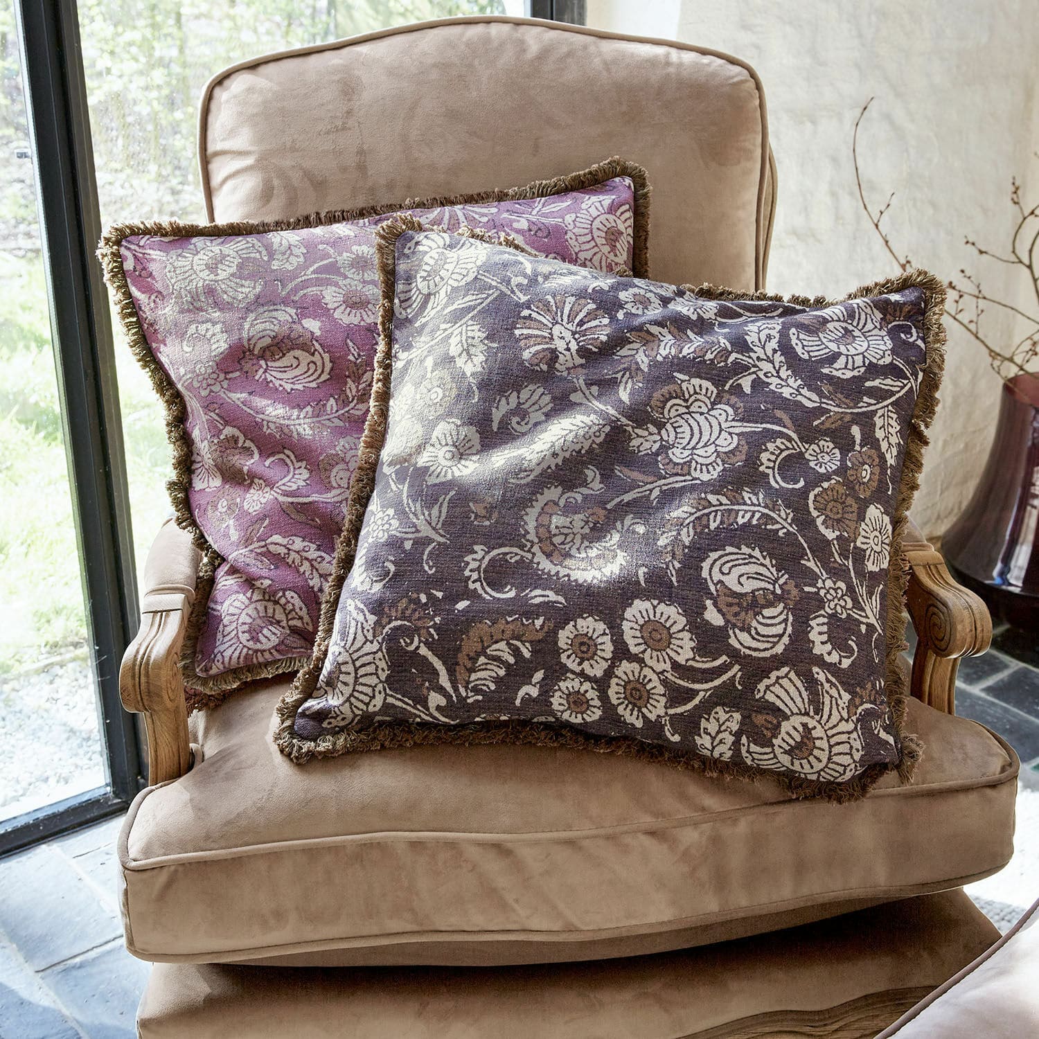 Lot de 2 housses de coussins Lalluga Deux coussins décoratifs à motif floral violet et gris sur un fauteuil beige confortable